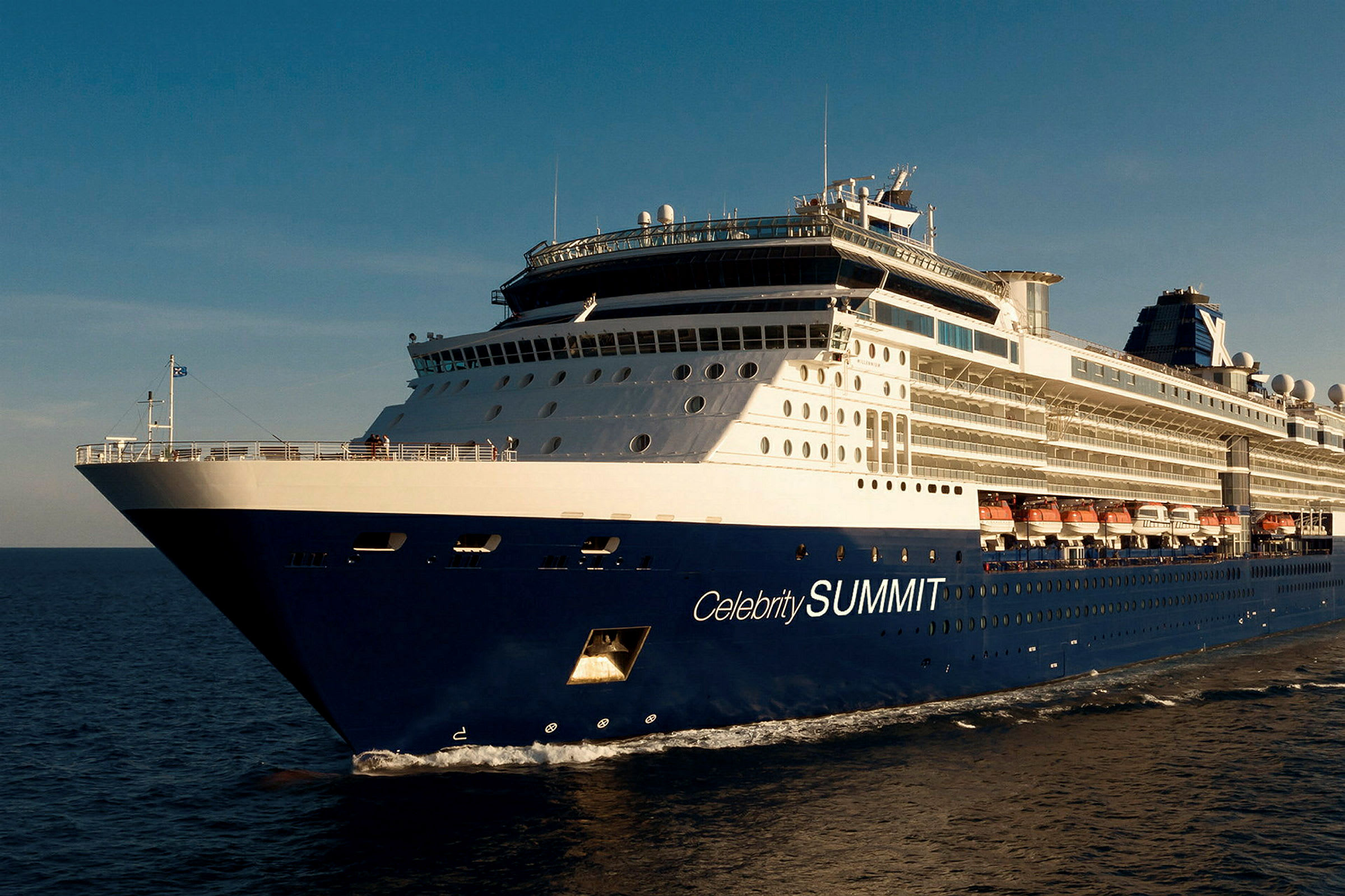Et blått og hvitt cruiseskip med teksten 'Celebrity SUMMIT' på siden, som seiler på havet under en blå himmel. (AI-generert tekst)