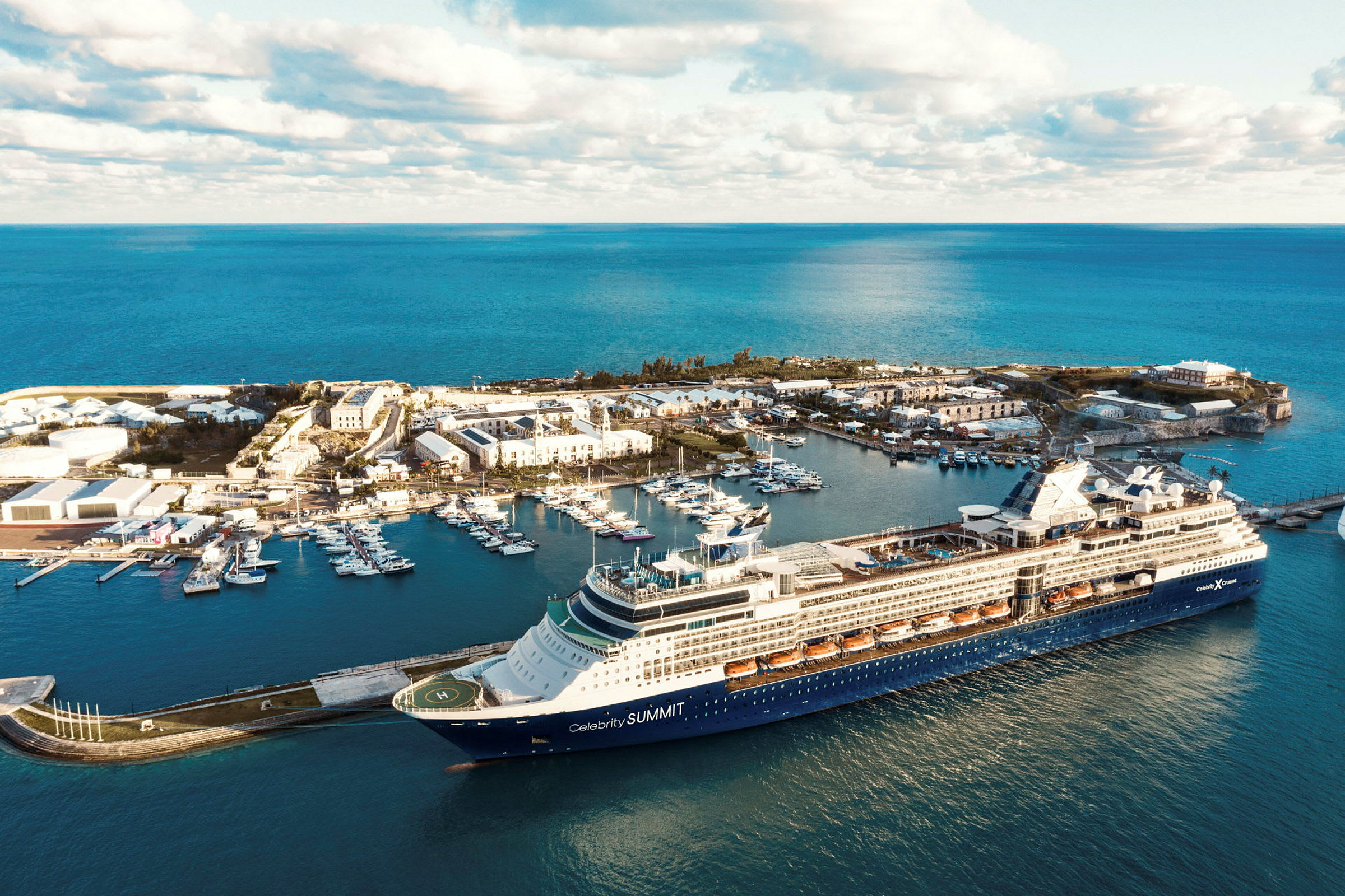 Cruiseskip ved kai med småbåthavn og bygninger. (AI-generert tekst)