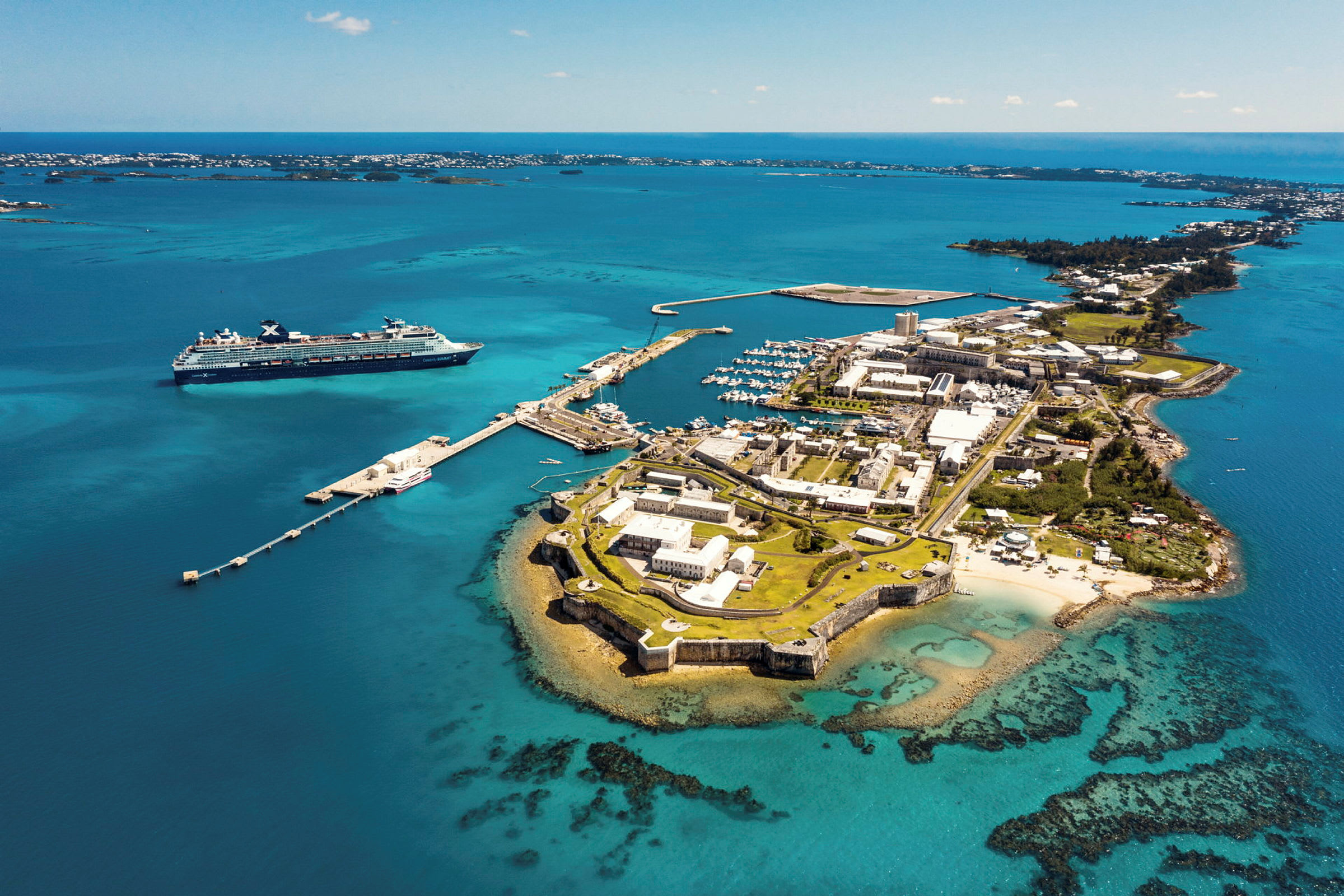 Luftfoto av en kystby med havn og cruiseskip i nærheten. (AI-generert tekst)