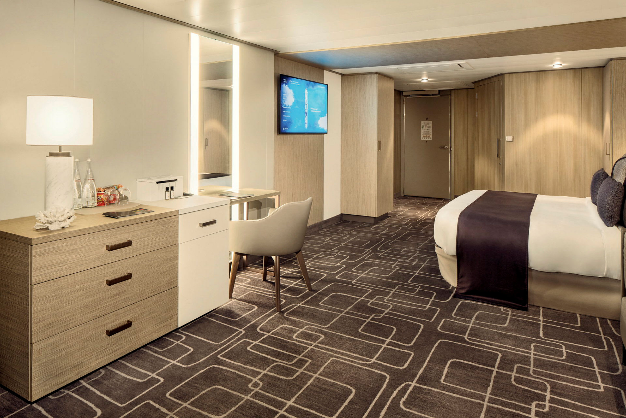 Et moderne og romslig hotellrom med en stor seng, skrivebord, stol og garderobeskap. (AI-generert tekst)