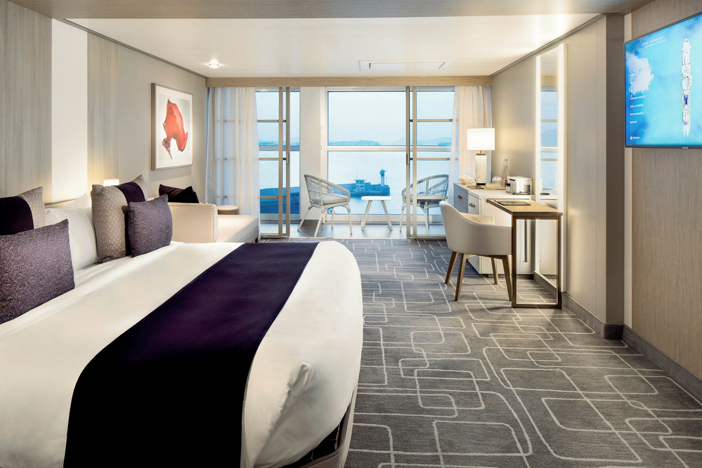 Et moderne og lyst hotellrom med en stor seng, et skrivebord og en balkong med utsikt mot vannet. (AI-generert tekst)