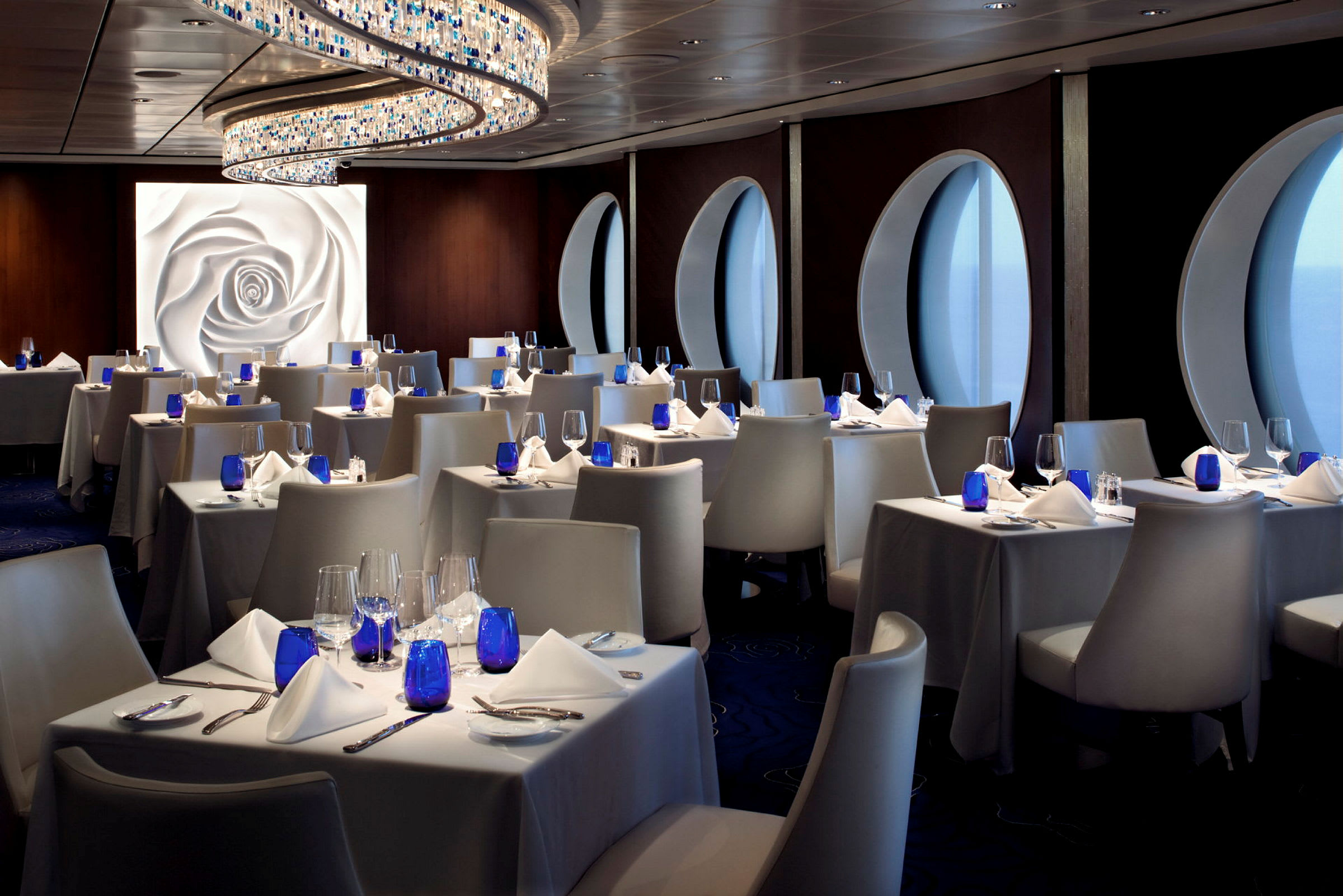 En elegant restaurant med hvite duker, blå glass og moderne stoler. (AI-generert tekst)