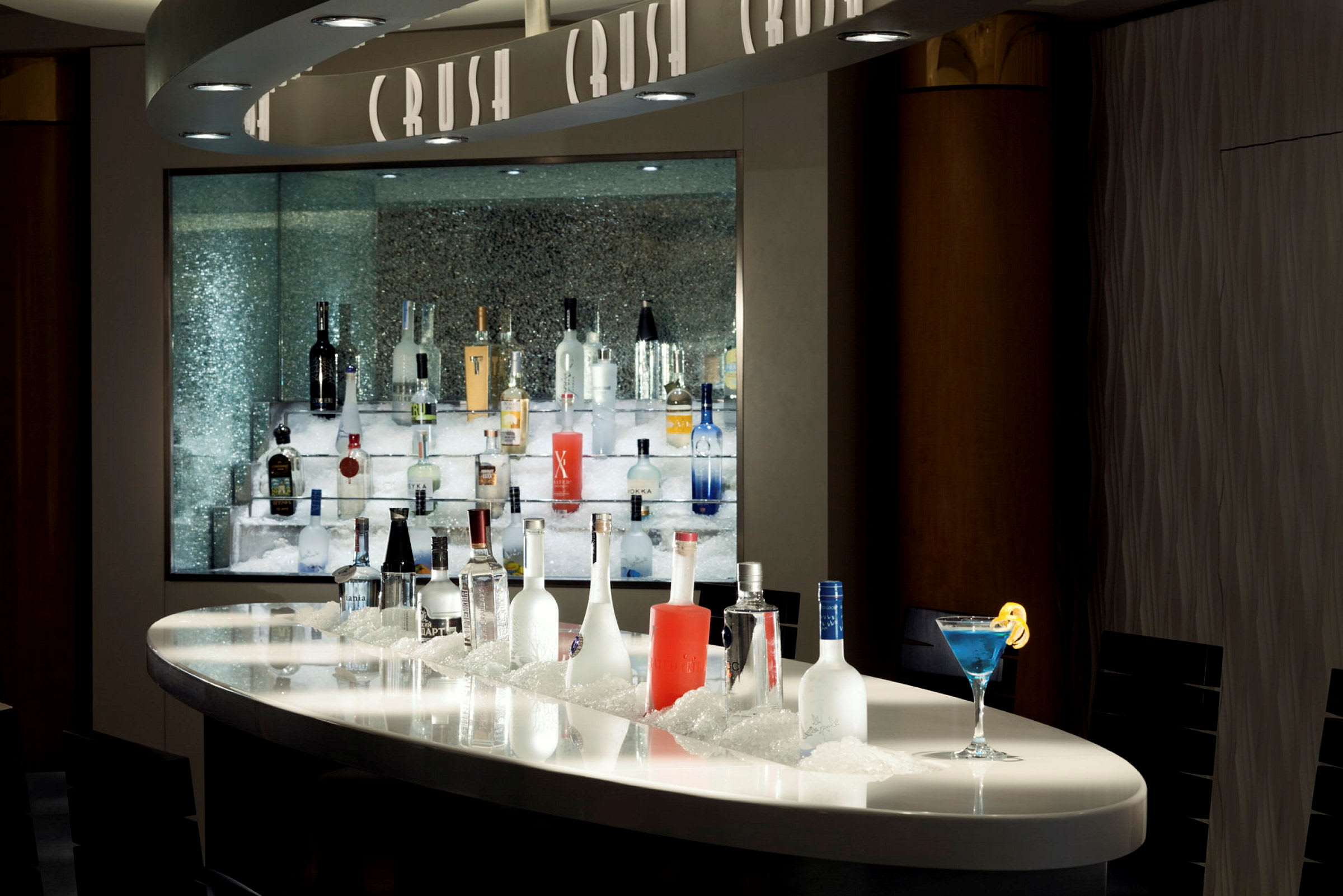 Bar med en rekke alkoholflasker på is, samt en blå cocktail. (AI-generert tekst)