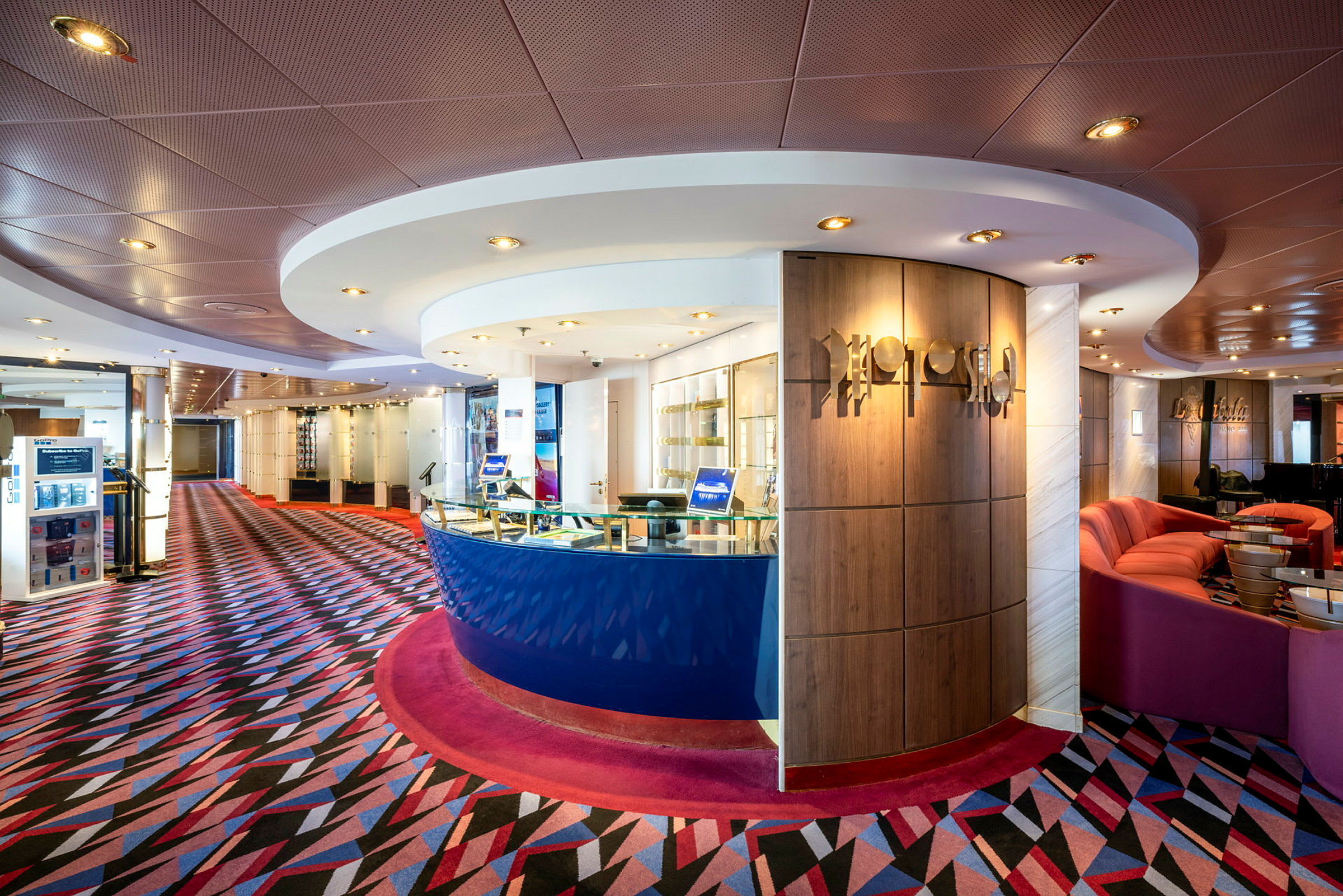 Resepsjonen om bord på et cruiseskip med moderne innredning, fargerikt mønstret teppe og takbelysning. (AI-generert tekst)