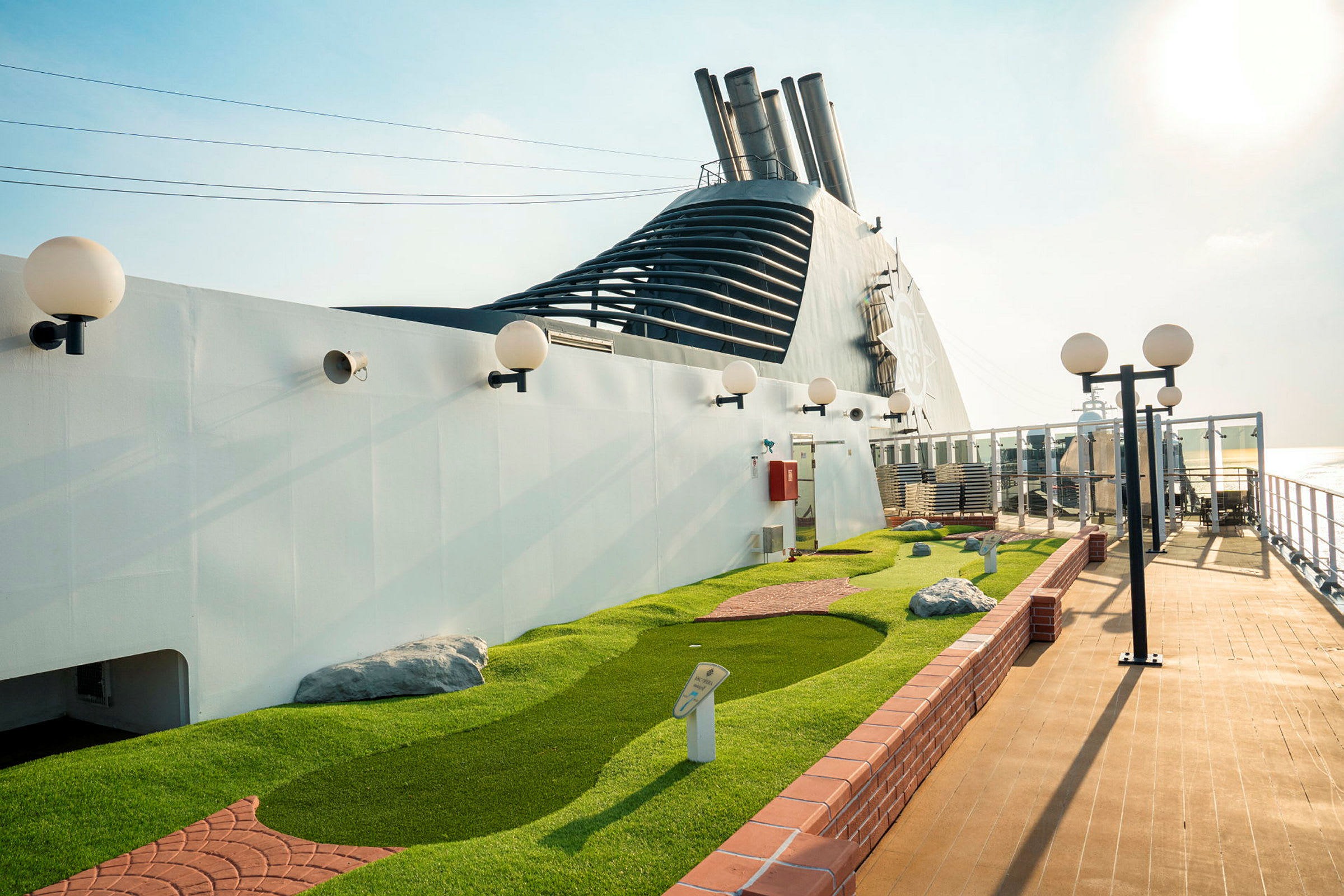 En minigolfbane med kunstgress og hvite lyktestolper på et cruiseskip. (AI-generert tekst)