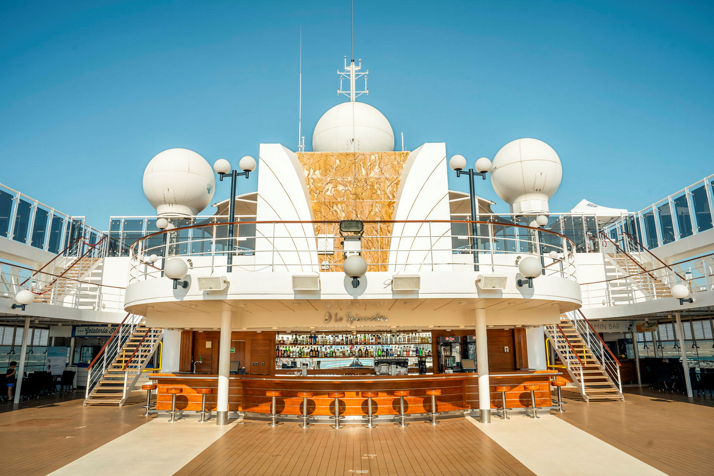 Bilde av en utendørs terrasse på et cruiseskip med sitteplasser ved en bar. (AI-generert tekst)