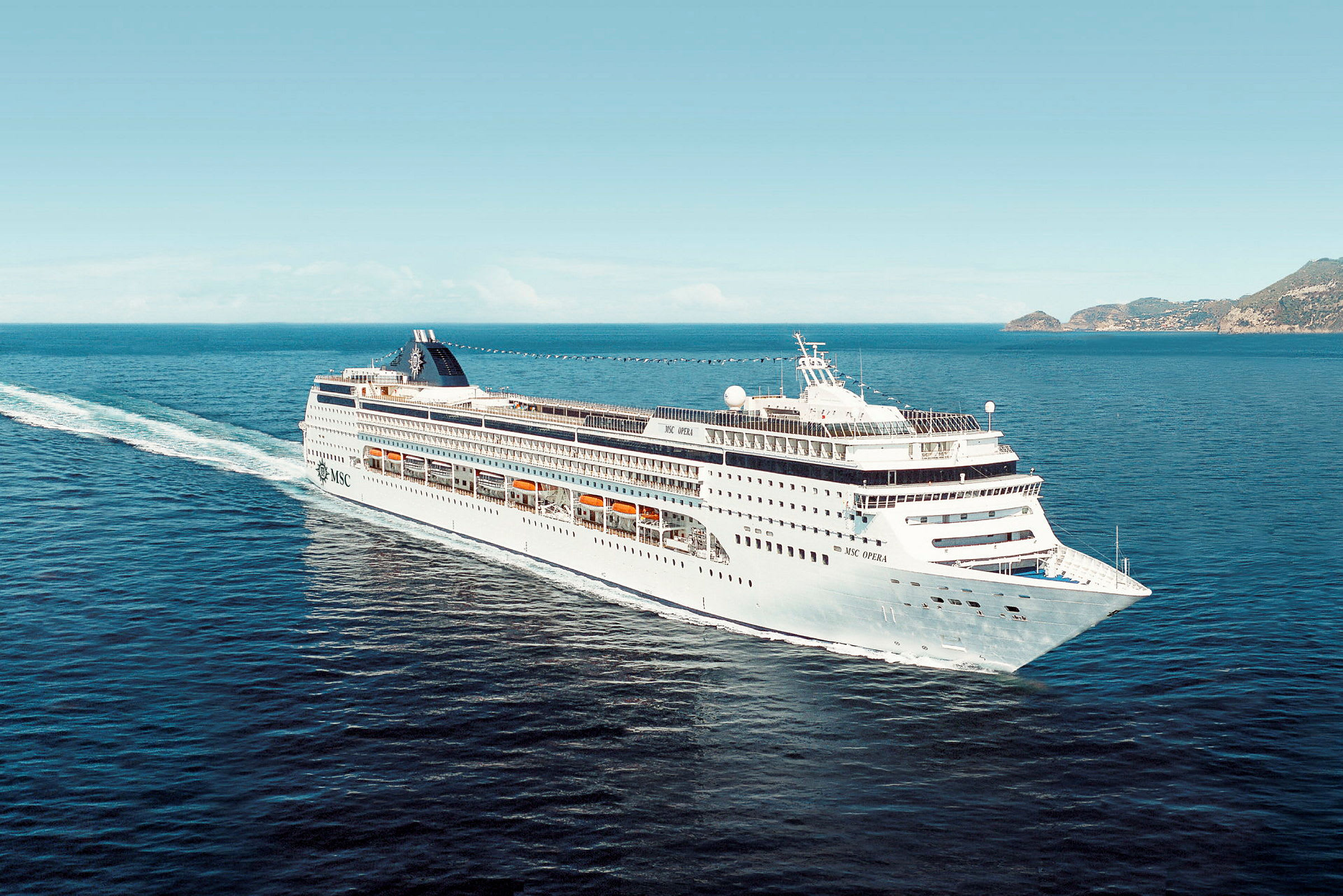 Et stort cruiseskip seiler på åpent hav med en kystlinje synlig i bakgrunnen. (AI-generert tekst)