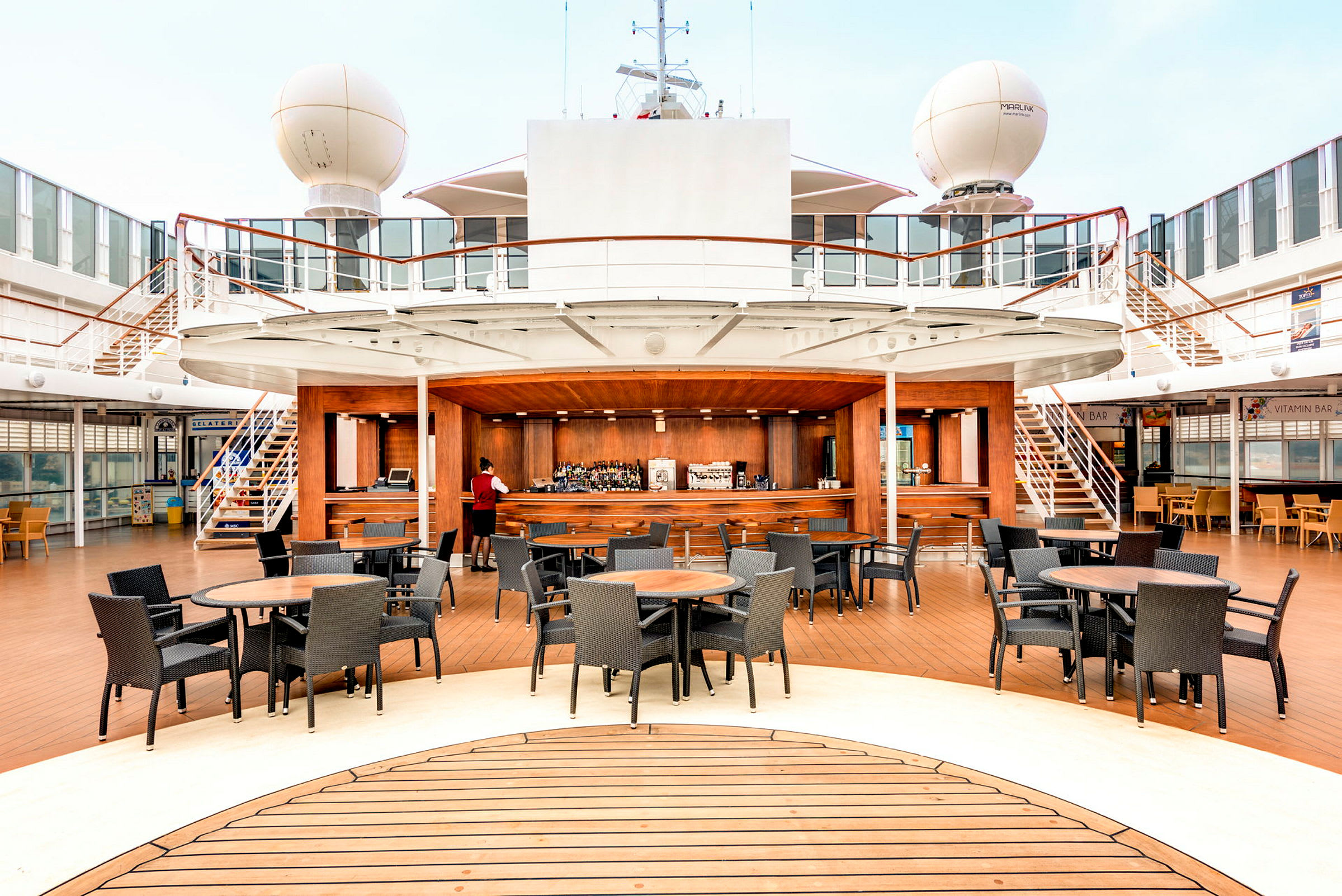 Bilde av en utendørsbar på et cruiseskip med bord og stoler. (AI-generert tekst)