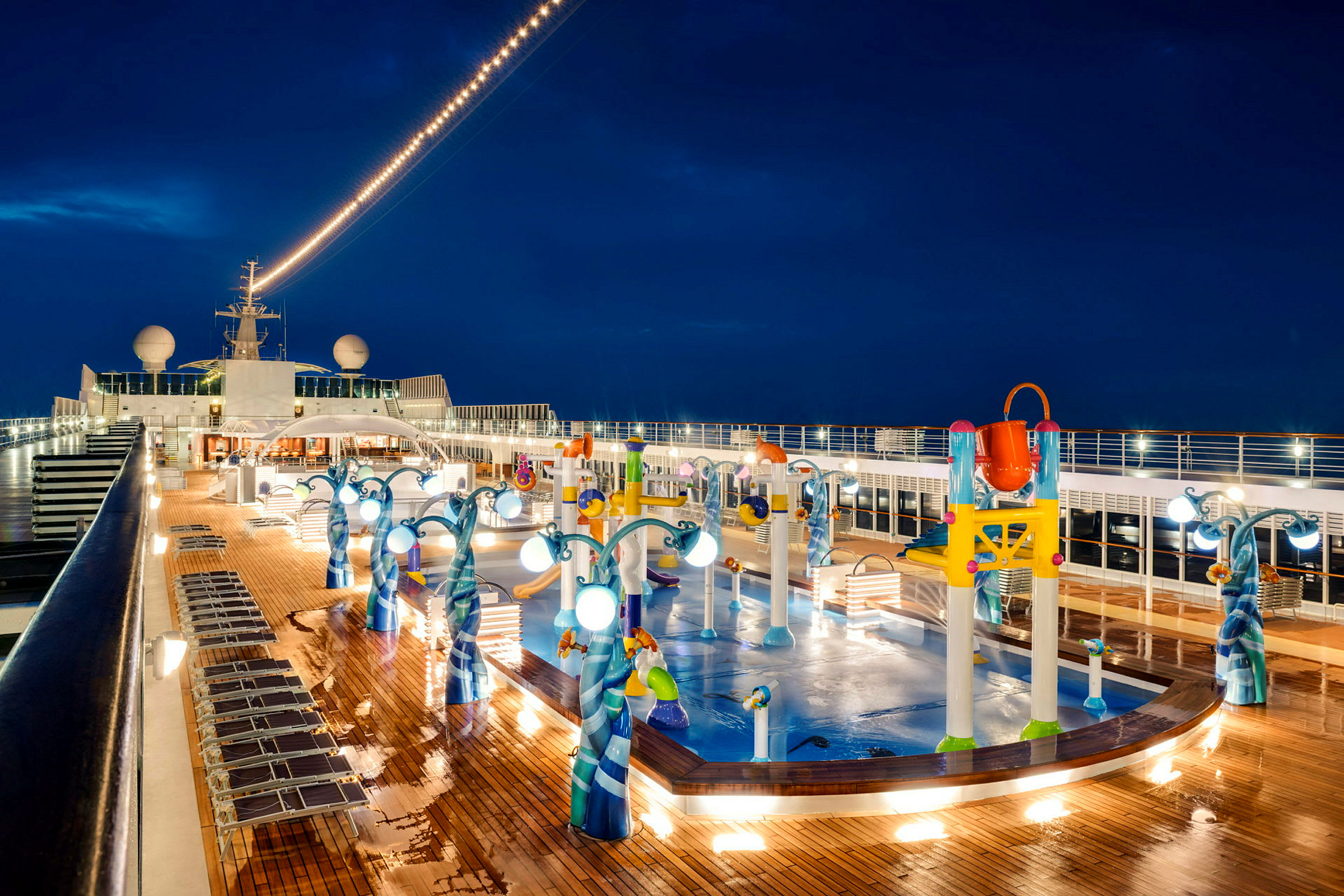 Et nattbilde av et cruiseskipdekk med basseng og lekeutstyr for barn. (AI-generert tekst)