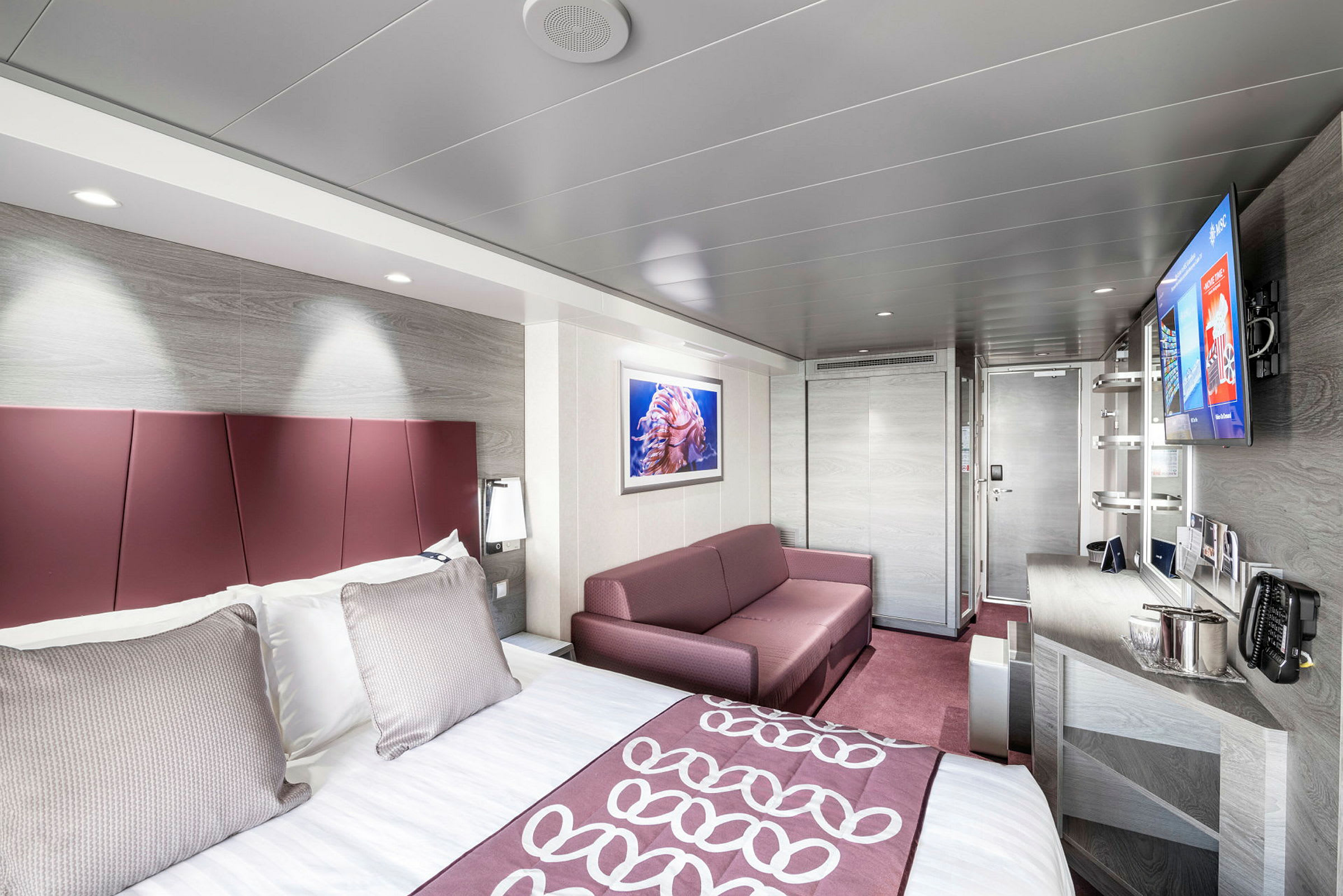 Hotellrom med seng, sofa og innredning. (AI-generert tekst)