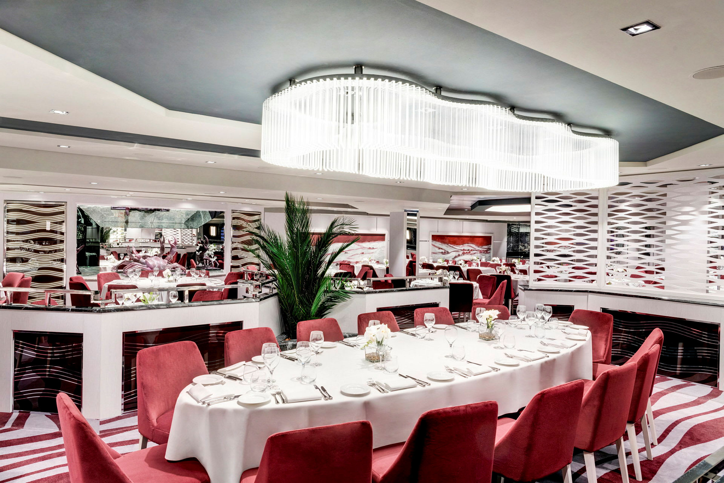 Elegant restaurant med røde stoler, hvit duk og moderne interiør. (AI-generert tekst)