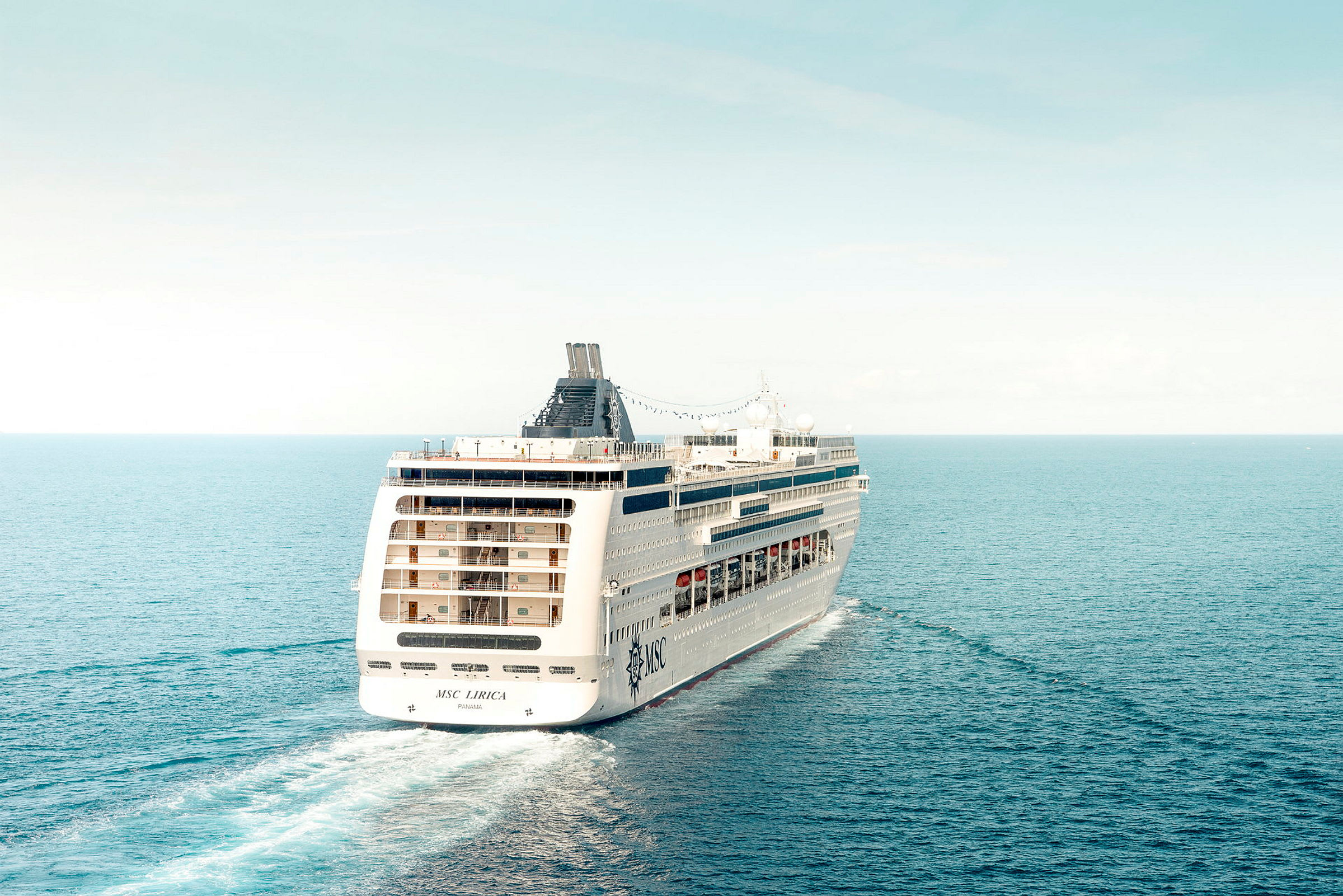 Et cruiseskip seiler på åpent hav under klar himmel. (AI-generert tekst)