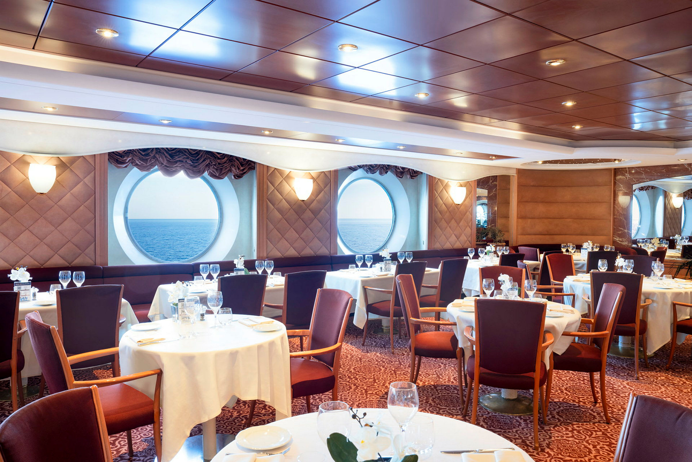En elegant spisesal med runde vinduer som vender mot havet. (AI-generert tekst)