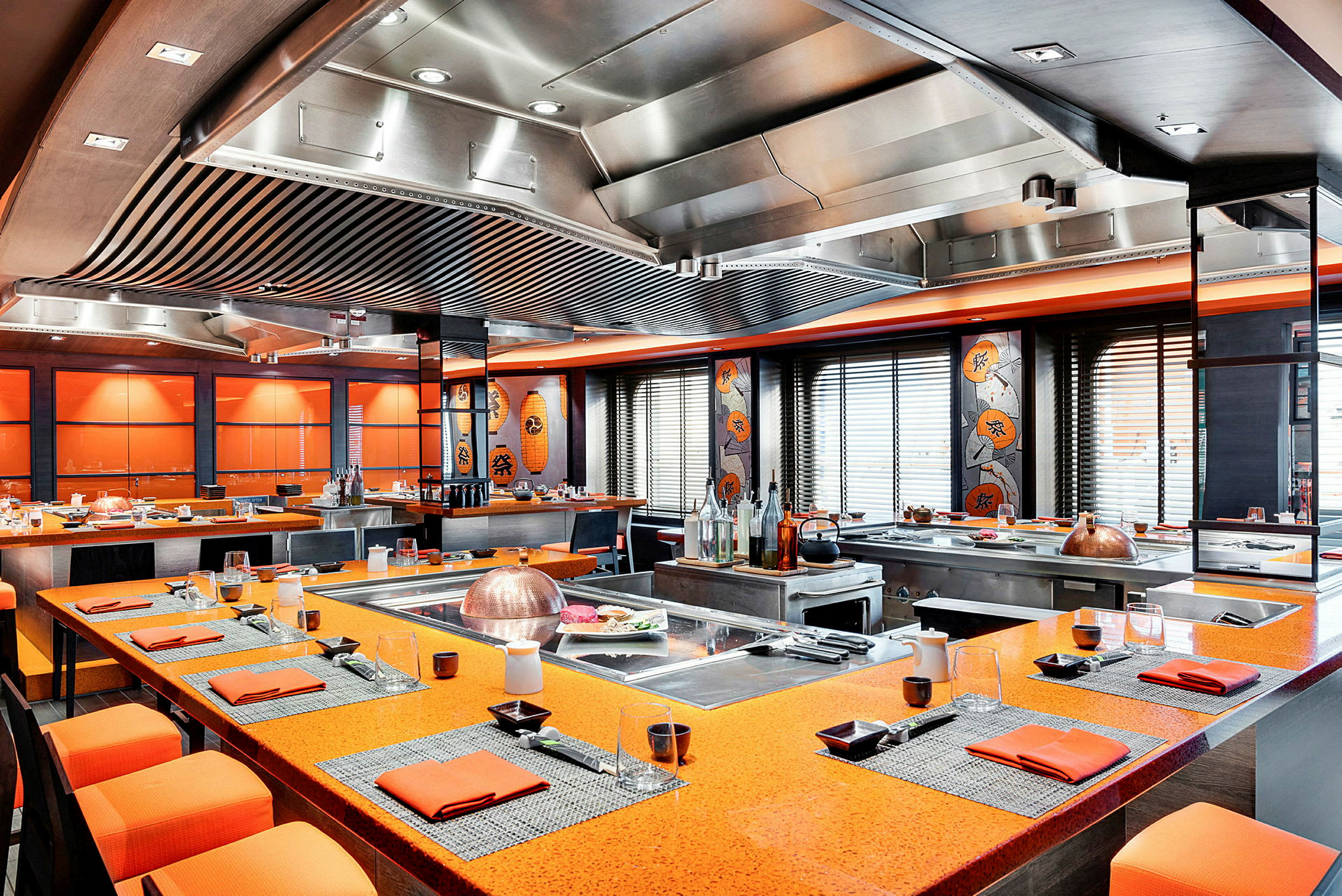 Et restaurantområde med oransje bordsoverflater, dekorert med asiatisk kunst og stil. (AI-generert tekst)