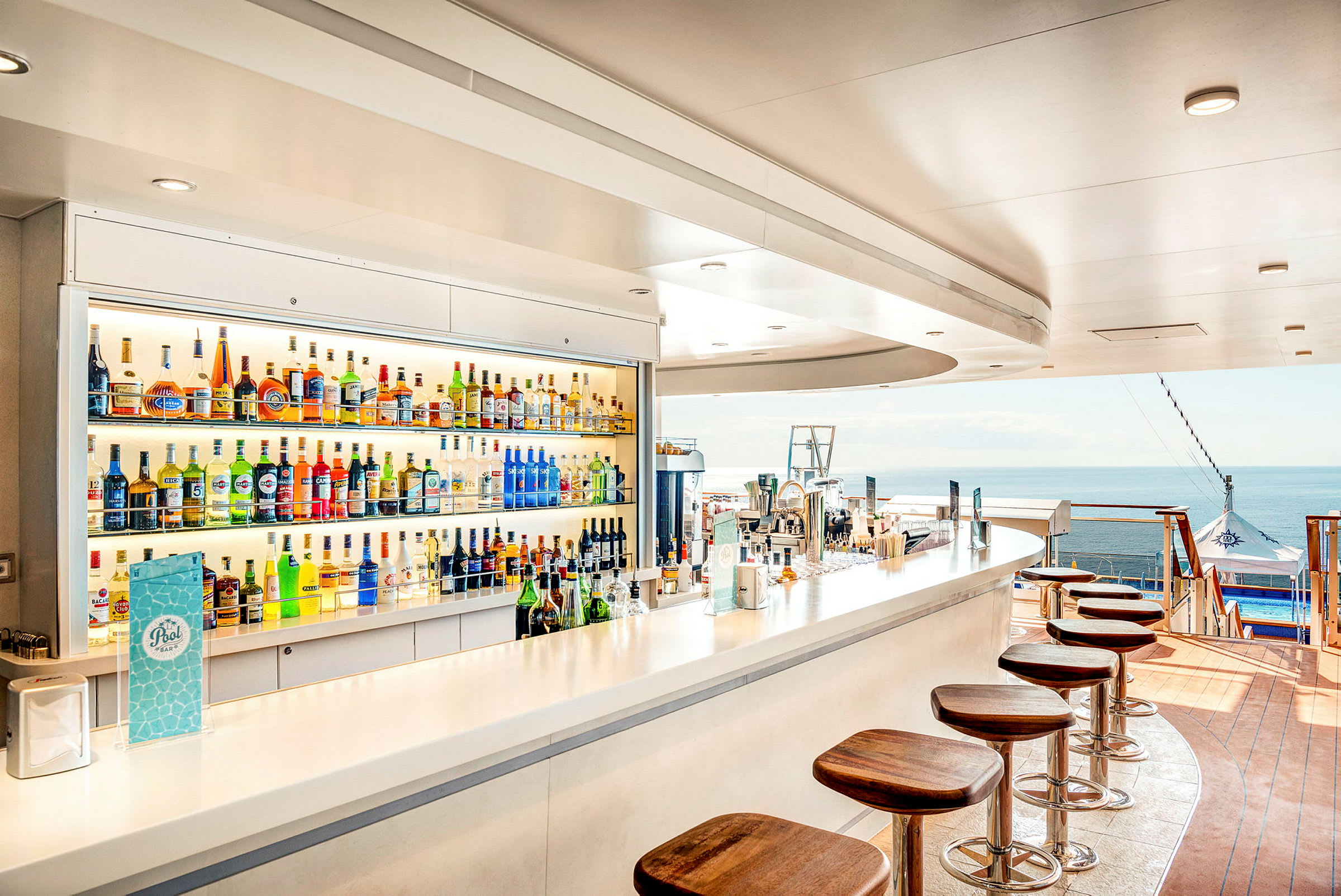 En bar med alkoholfaske og stoler ved en havutsikt. (AI-generert tekst)