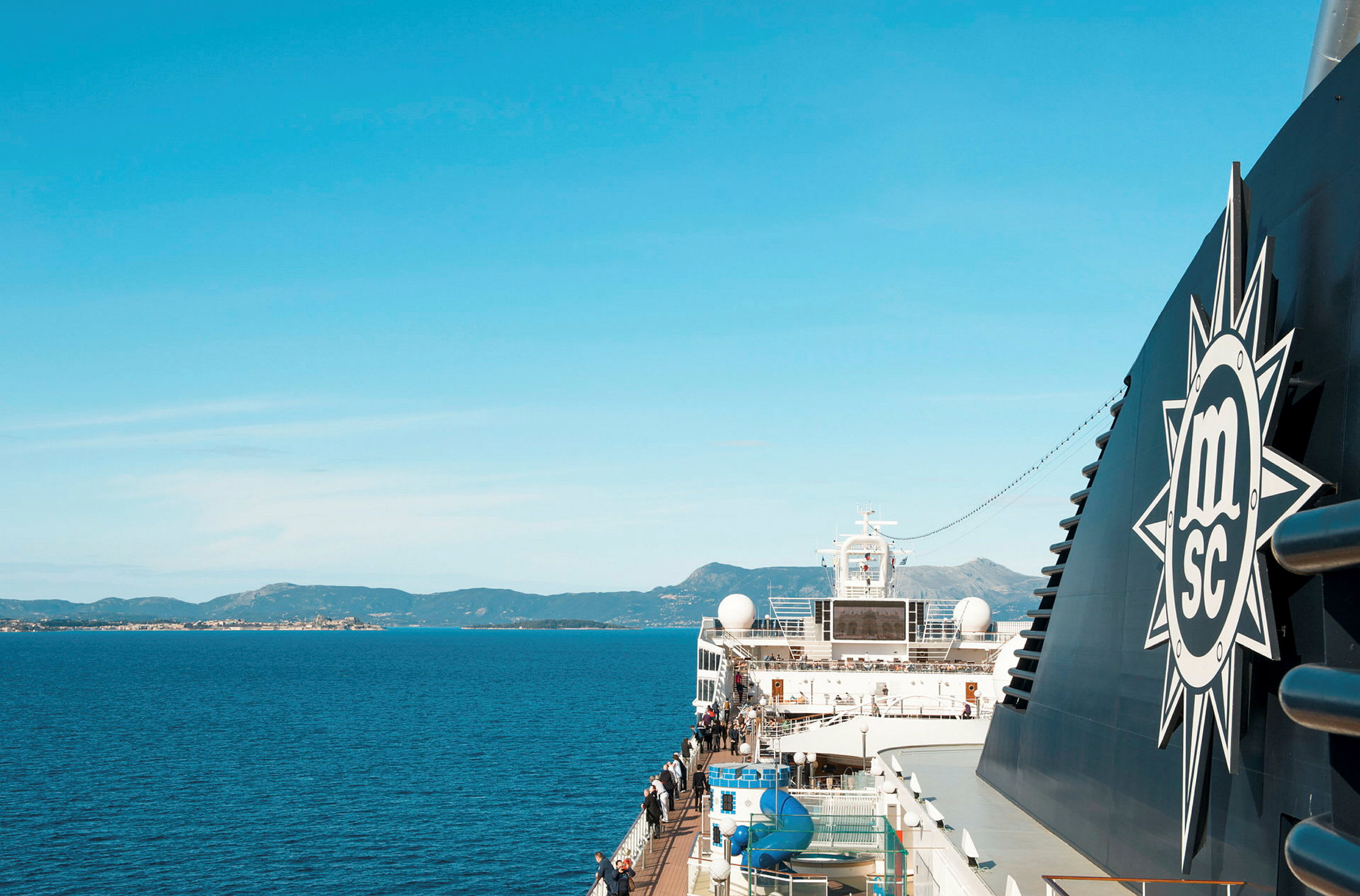 Et cruiseskip på sjøen med fjerne fjell og kysten. (AI-generert tekst)