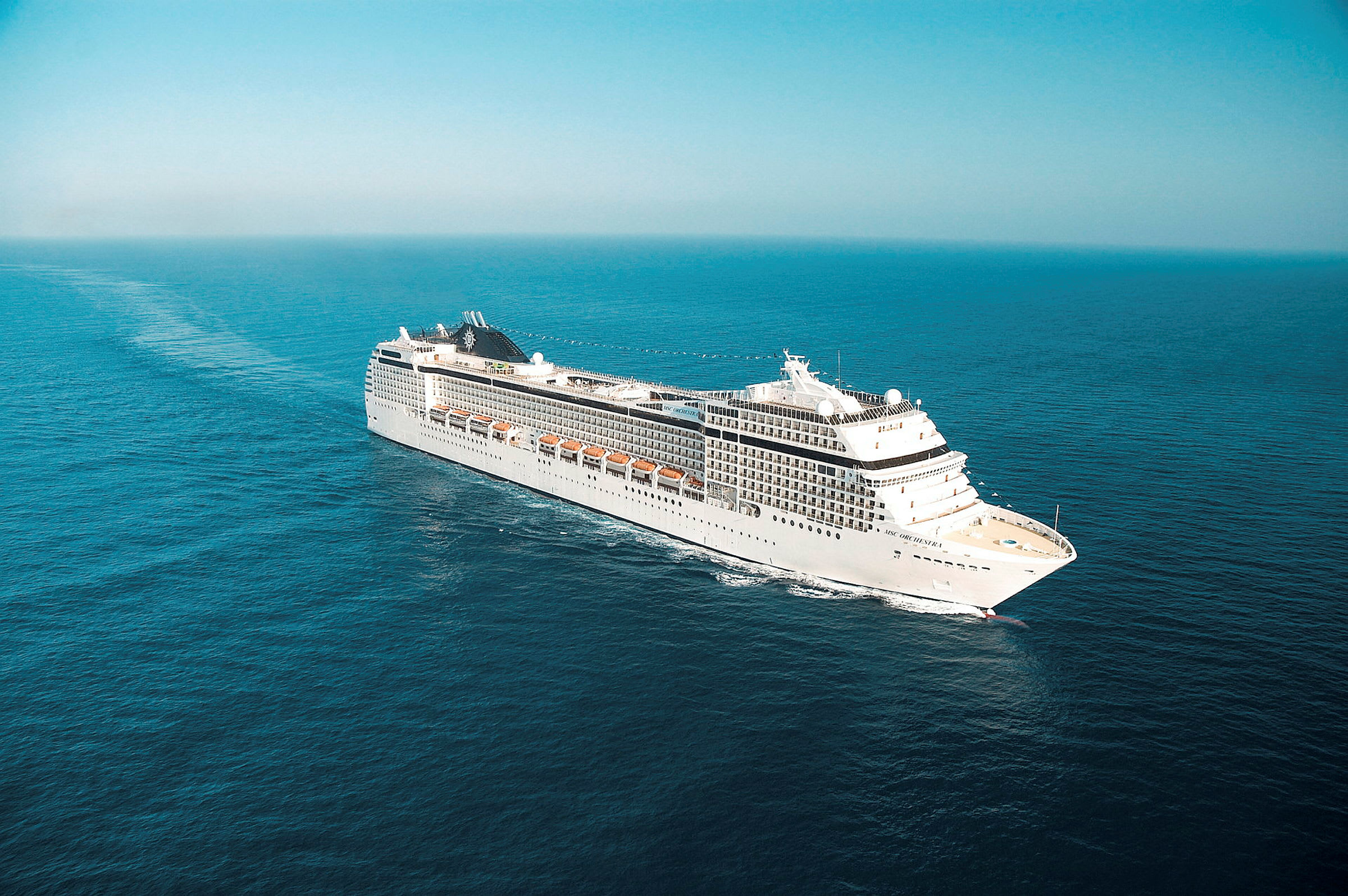 Cruiseskip seiler på åpent hav under klar himmel. (AI-generert tekst)
