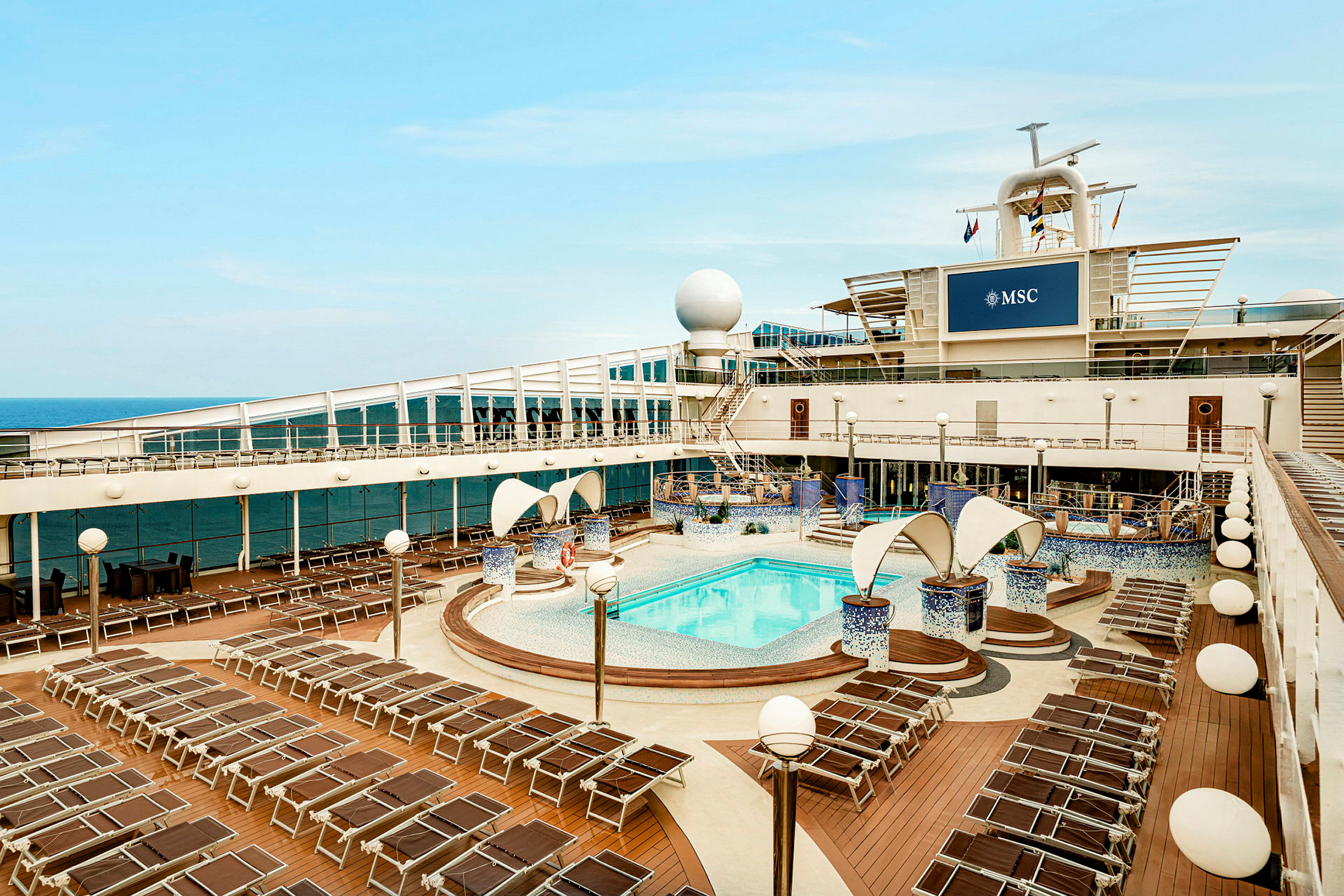 Bilde av dekket på et cruiseskip med et basseng omgitt av solsenger og dekorative elementer. (AI-generert tekst)