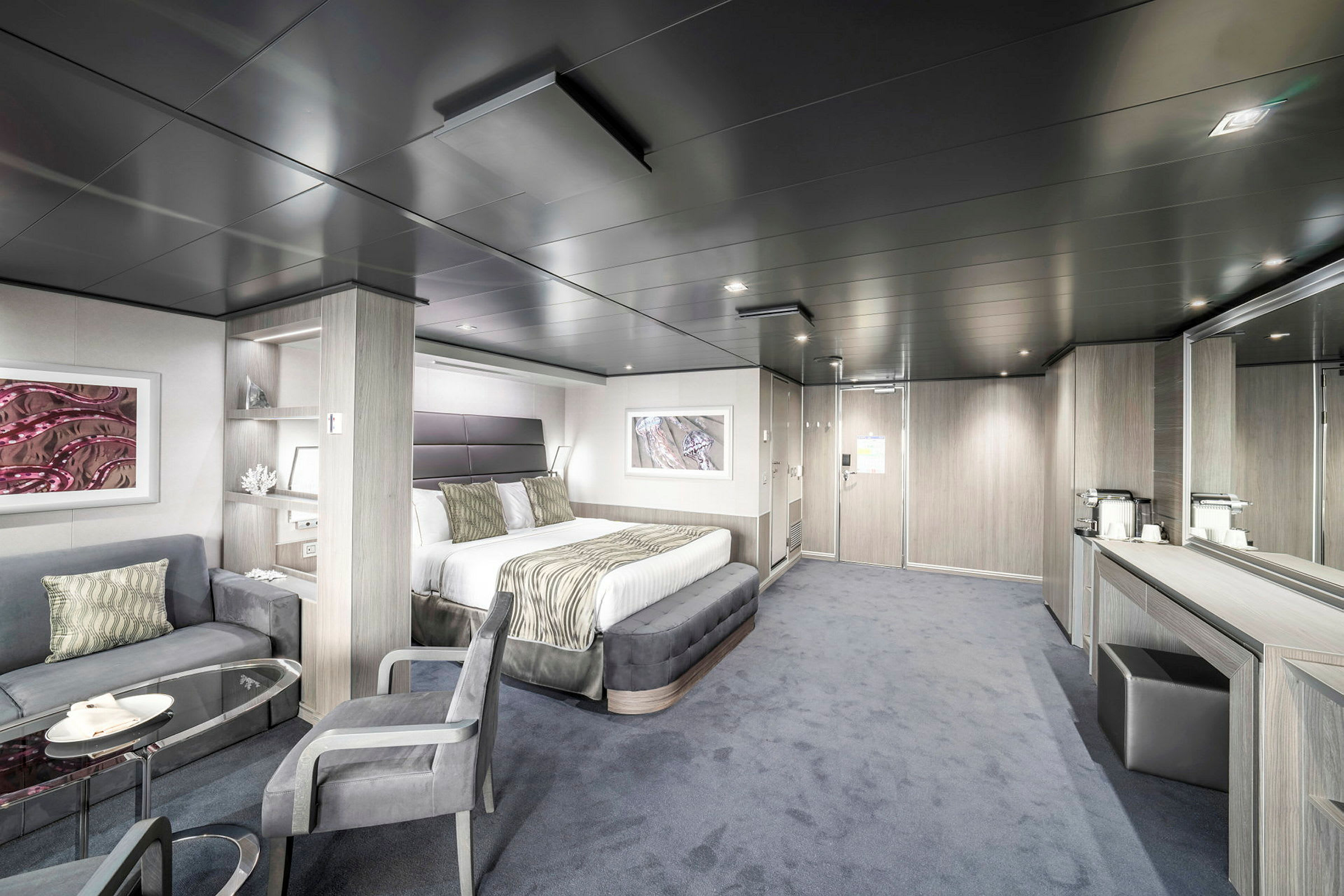 Bilde av et moderne hotellrom med dobbeltseng, sittegruppe, bord og speil. (AI-generert tekst)