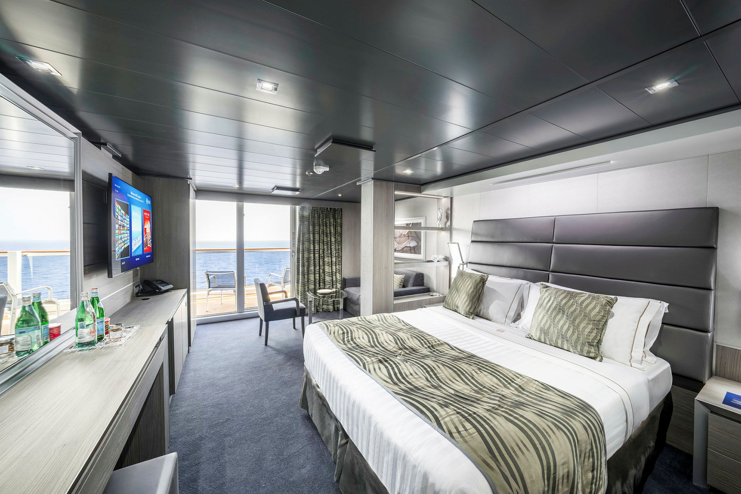 Moderne hotellrom med stor seng, sitteplass og havutsikt. (AI-generert tekst)