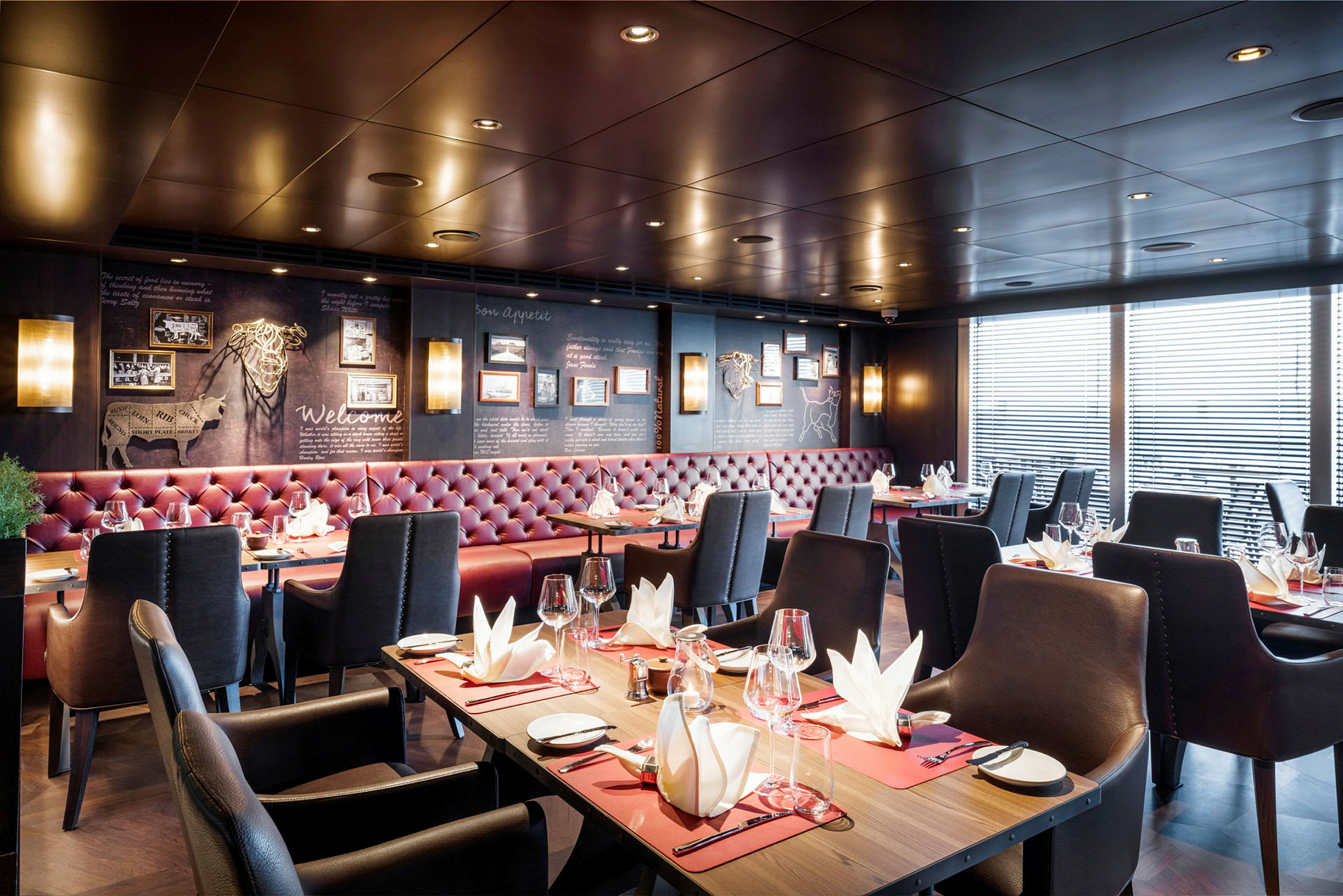 Interiør av en elegant restaurant med dekkede bord og røde polstrede sofaer. (AI-generert tekst)