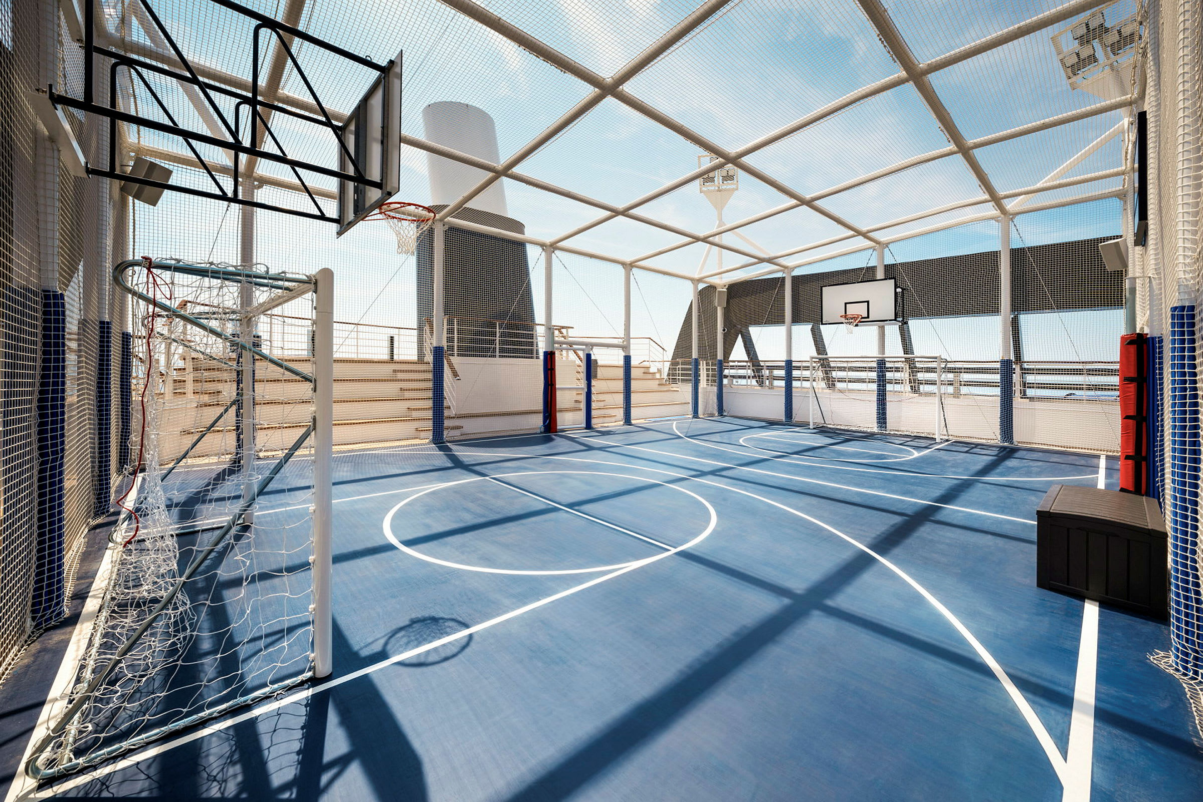Inhegnet idrettsområde med blått underlag og basketballkurver. (AI-generert tekst)