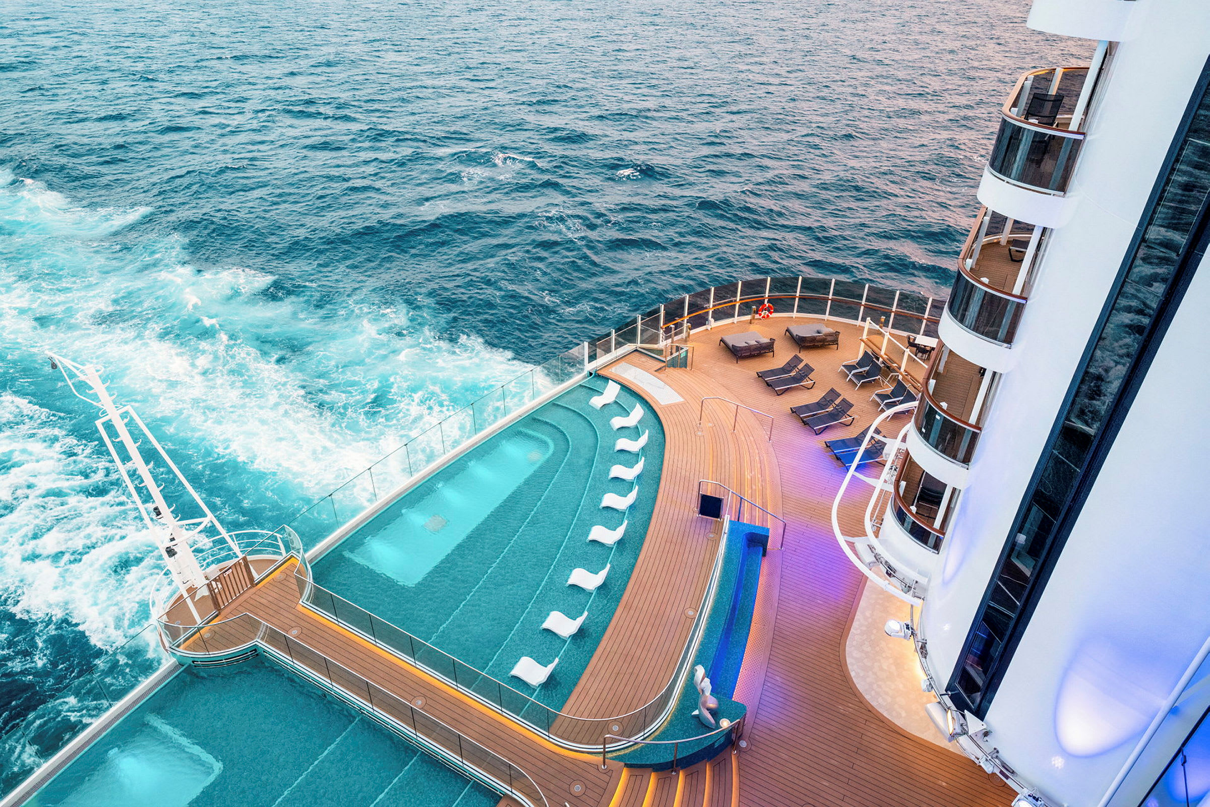 En basseng og soldekk på et cruiseskip med havet i bakgrunnen. (AI-generert tekst)