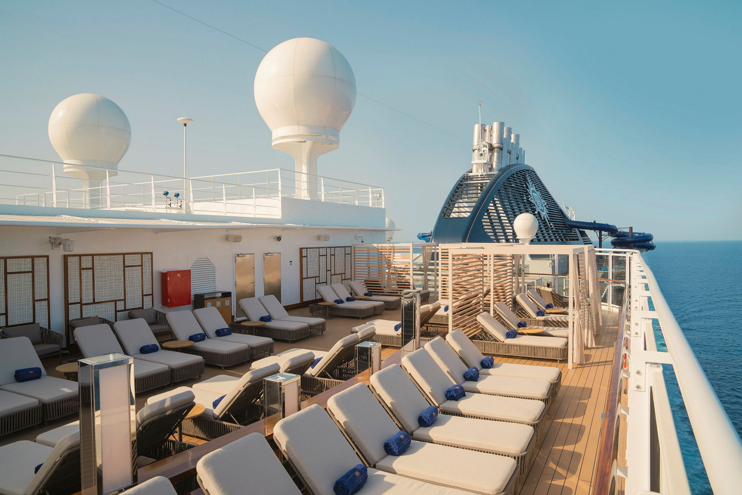 Solstoler på dekk av et cruiseskip under klar himmel. (AI-generert tekst)