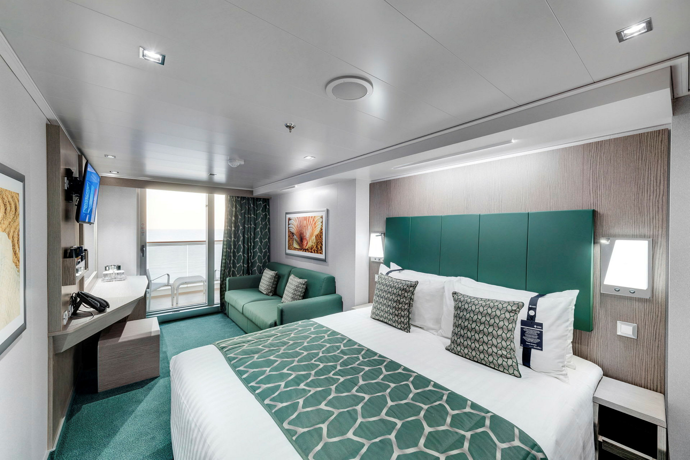 Et moderne hotellrom med seng, sofa og balkong med utsikt. (AI-generert tekst)