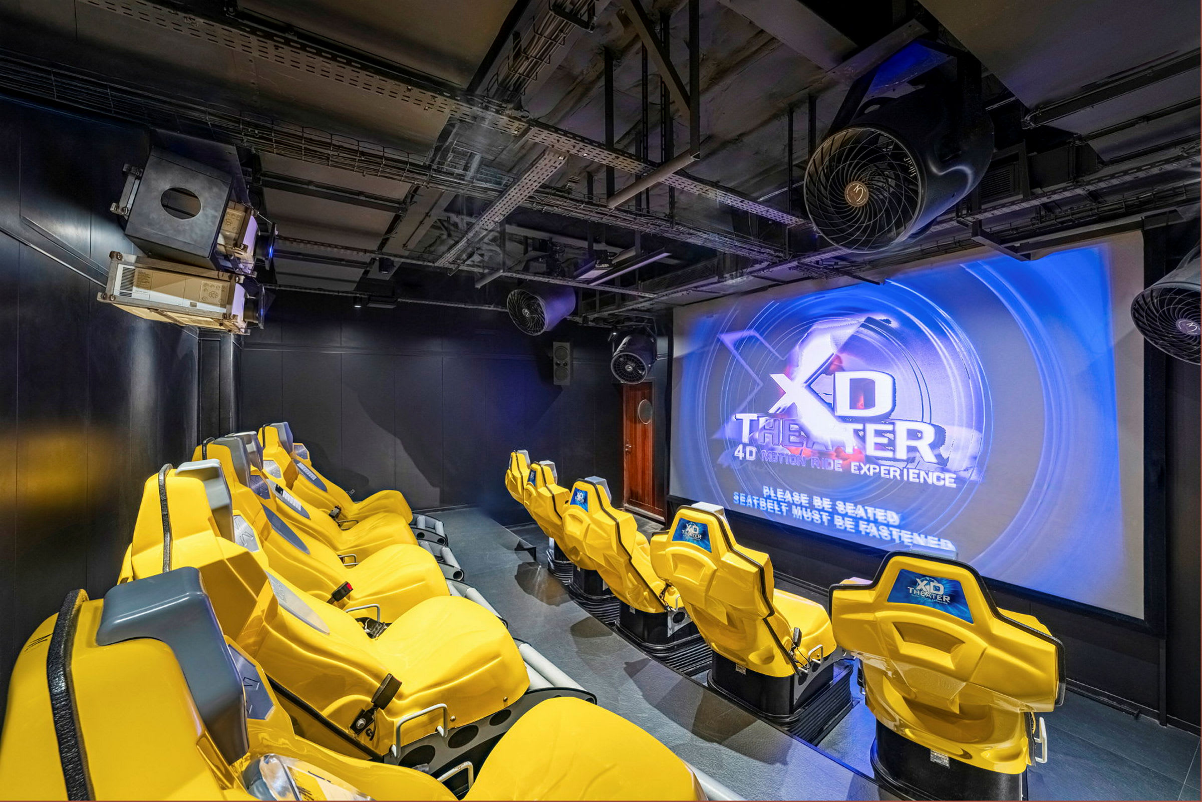 Interiør av en 4D-kino med gule stoler og en stor skjerm. (AI-generert tekst)