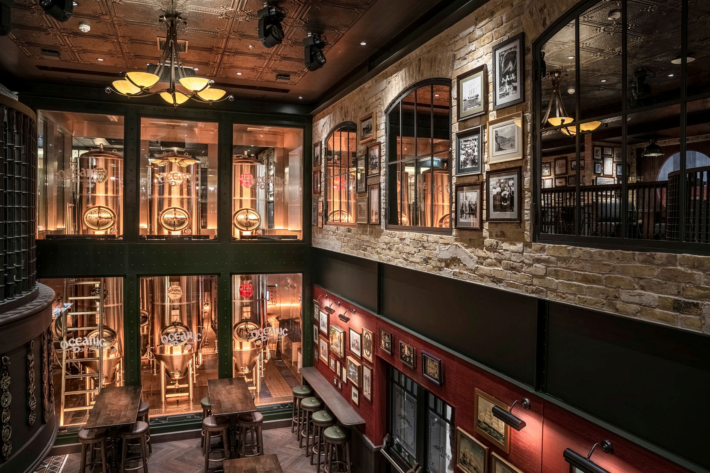Interiør av en bar med bryggetanker bak glass og vegger dekorert med bilder. (AI-generert tekst)