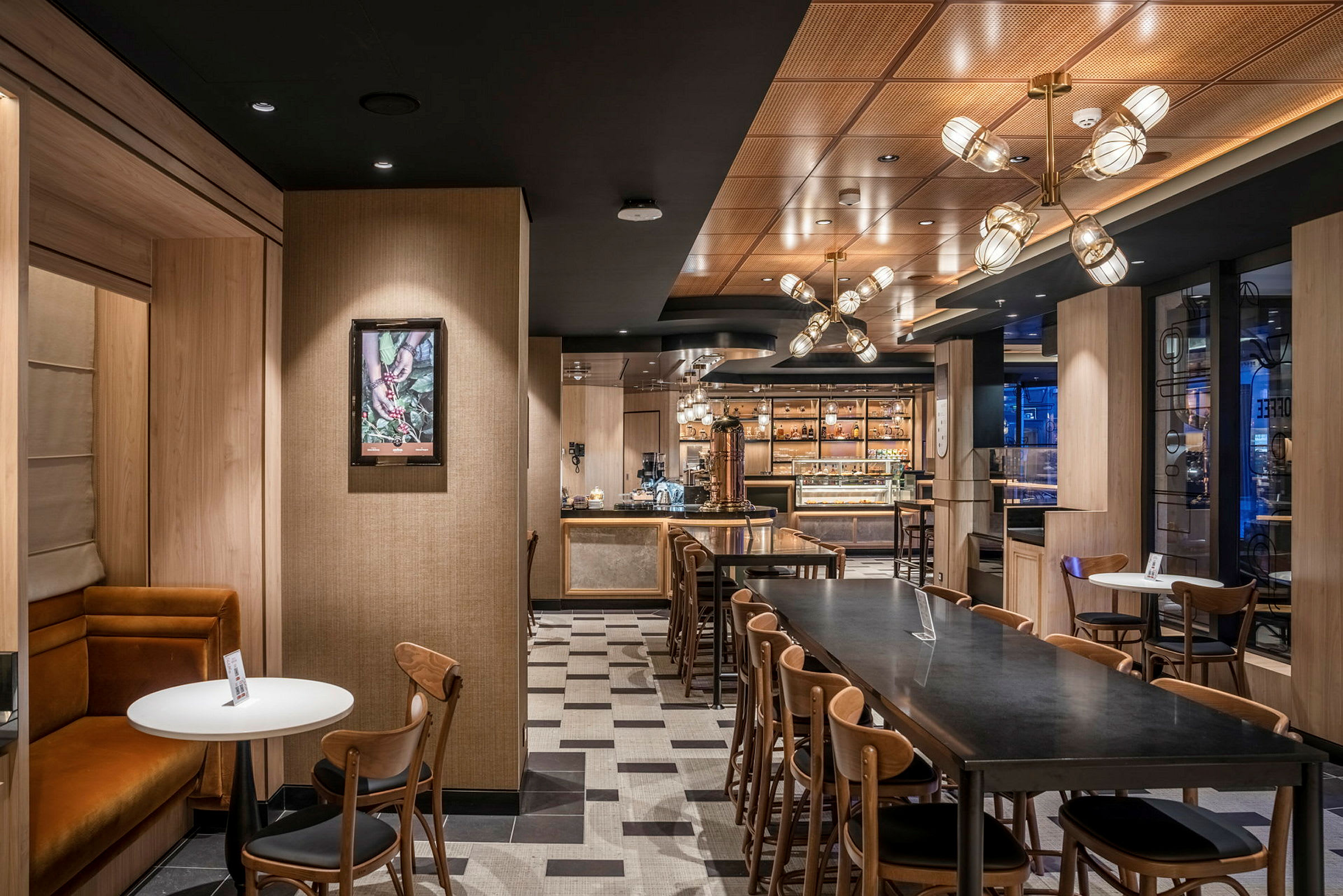 Interiør av en moderne kafé med bord og stoler, elegant belysning og synlige trematerialer. (AI-generert tekst)