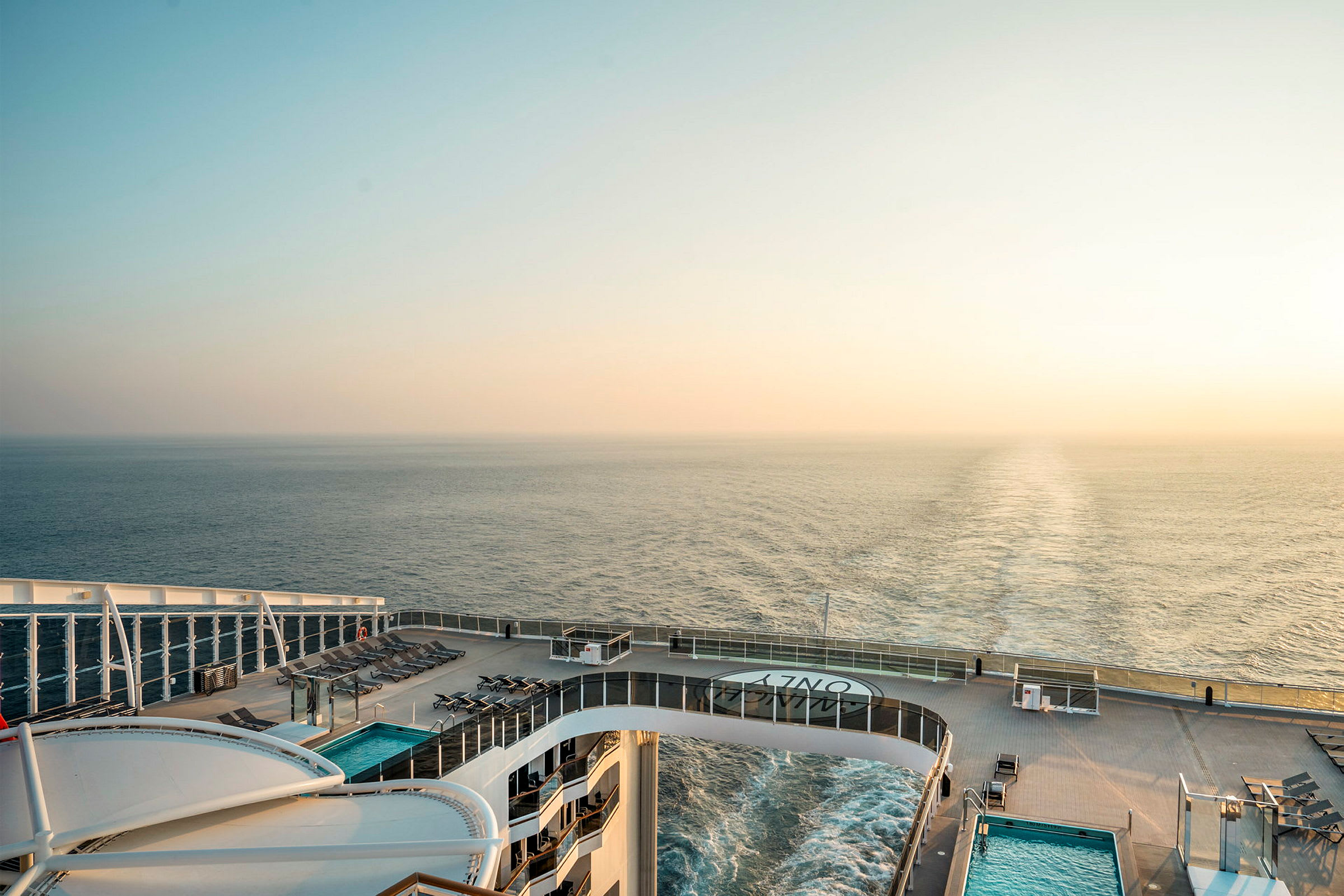 Bilde av utsikten fra et cruiseskip med havet i bakgrunnen og solnedgangen ved horisonten. (AI-generert tekst)