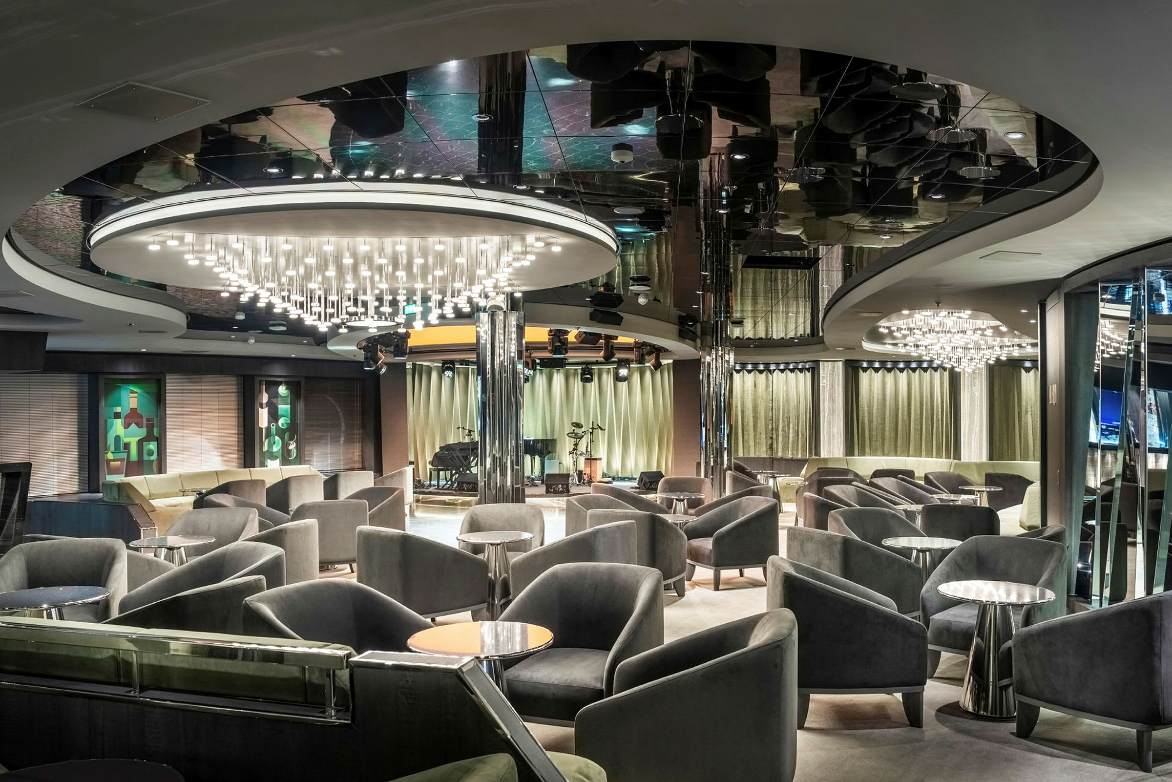 Lounge med komfortable stoler, små bord og hengende lysekroner. (AI-generert tekst)