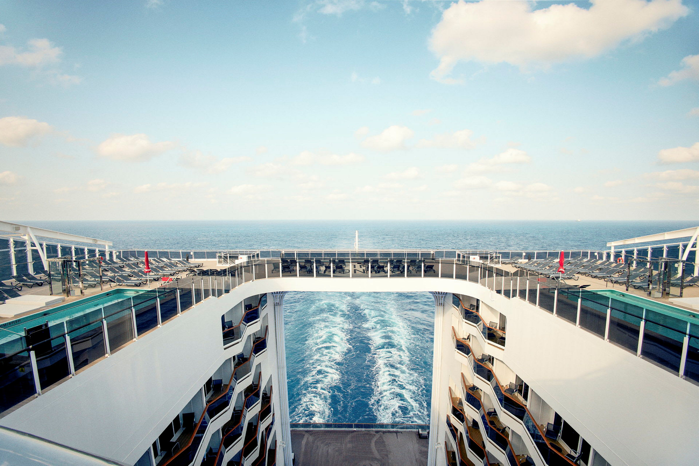 Utsikt fra cruise med soldekk, solsenger, basseng og havet i bakgrunnen. (AI-generert tekst)
