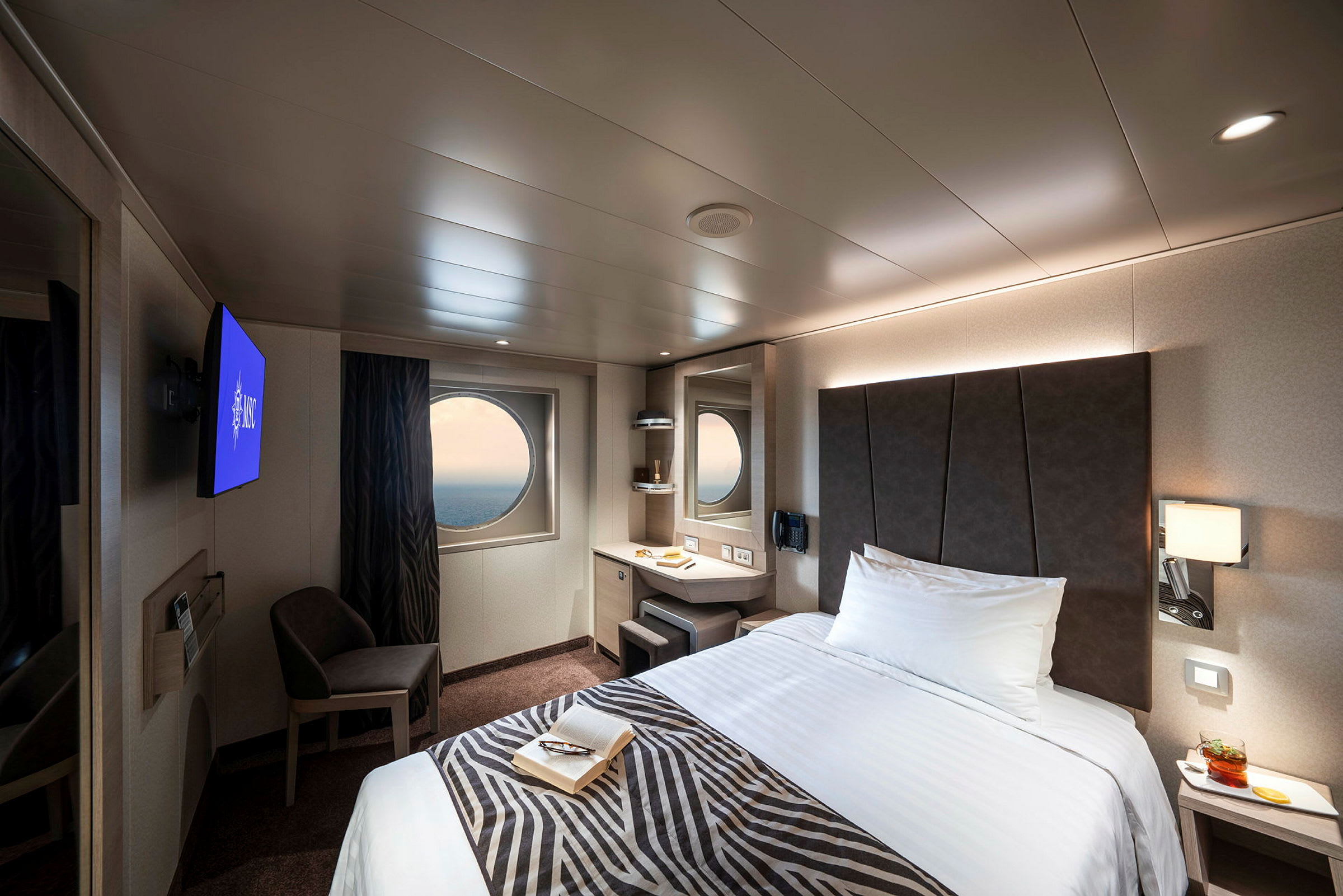 Et moderne hotellrom med en seng, et rundt vindu og en TV. (AI-generert tekst)