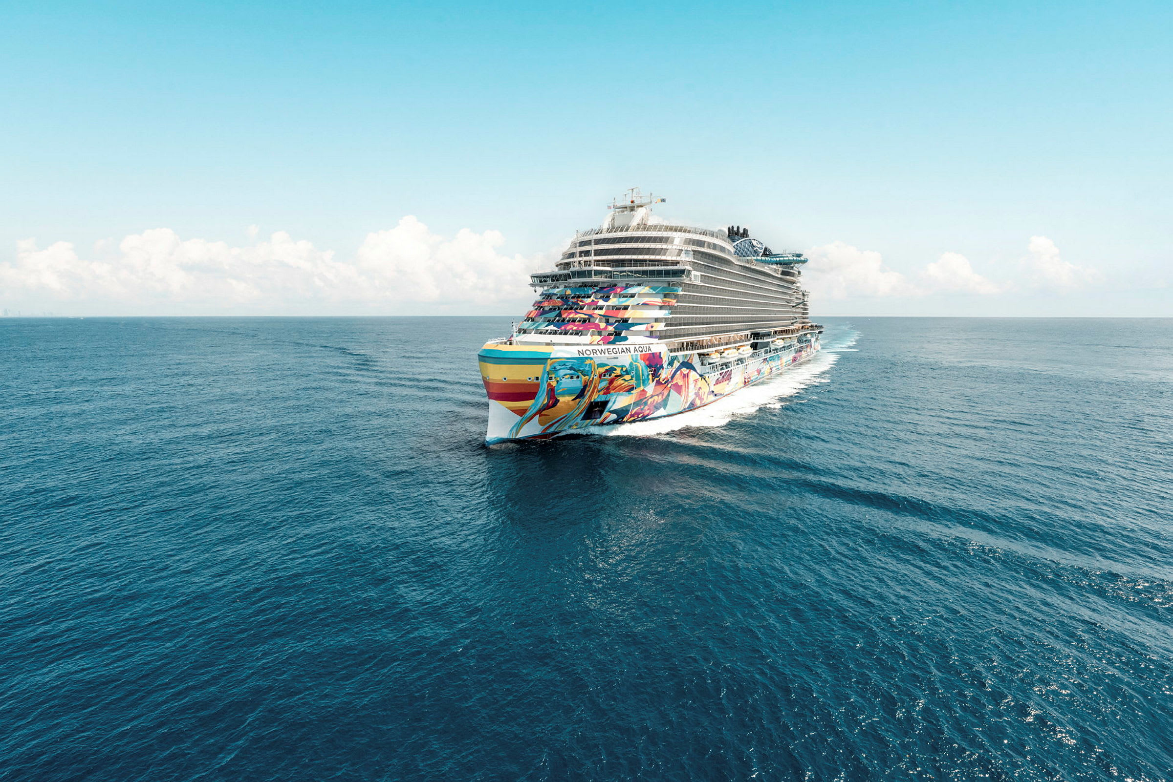 Cruiseskip med fargerik dekorasjon på sjøen under en klar blå himmel. (AI-generert tekst)