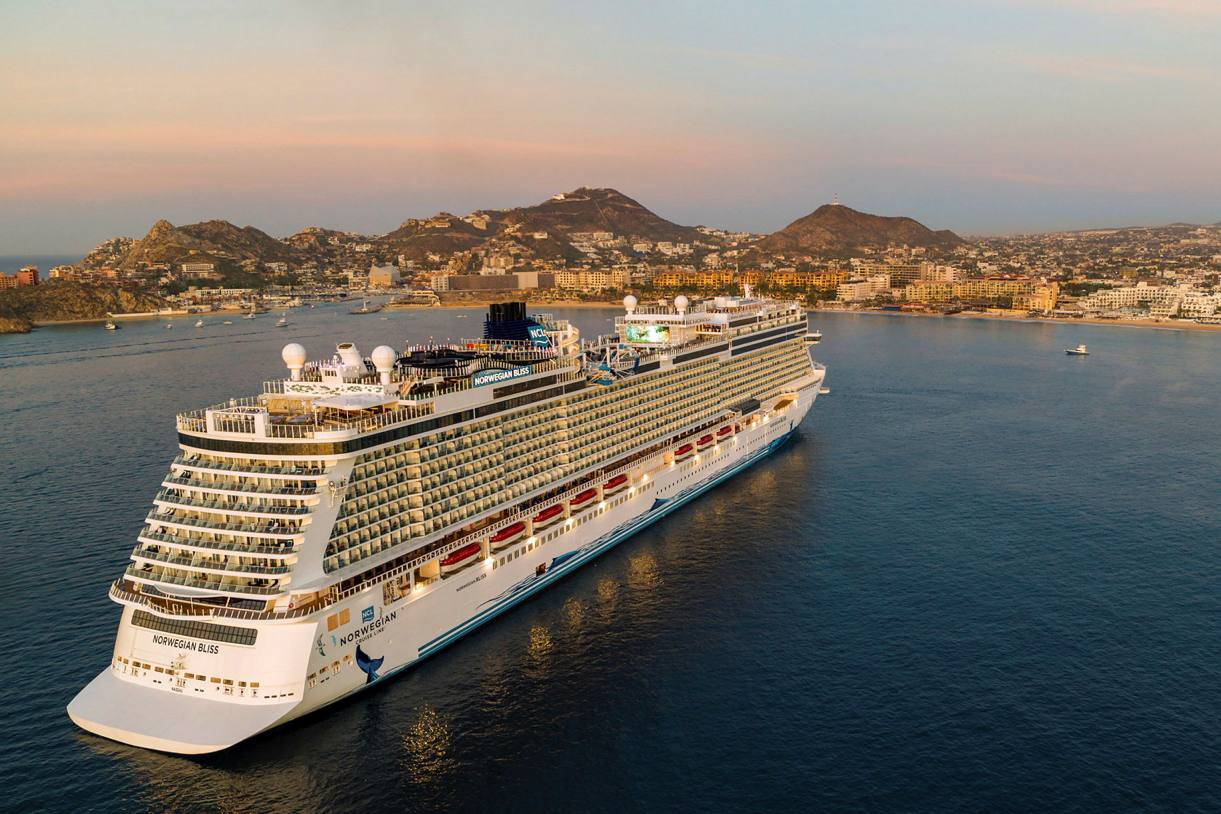 Et bilde av cruiseskipet Norwegian Bliss ved en kystby ved solnedgang. (AI-generert tekst)