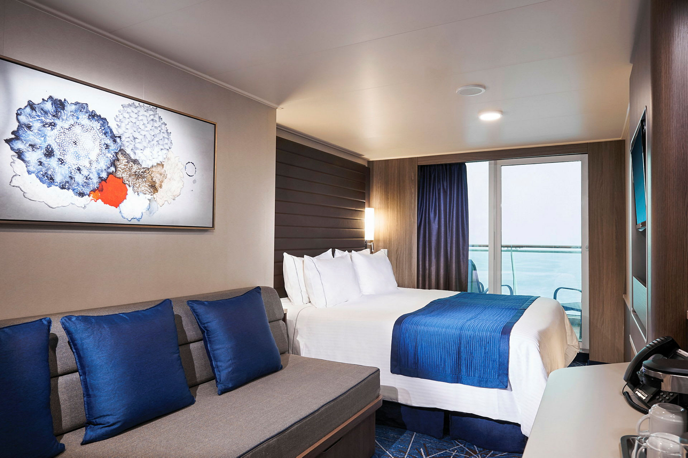 Et moderne hotellrom med en dobbeltseng, blå dekorative elementer og en sittegruppe. (AI-generert tekst)
