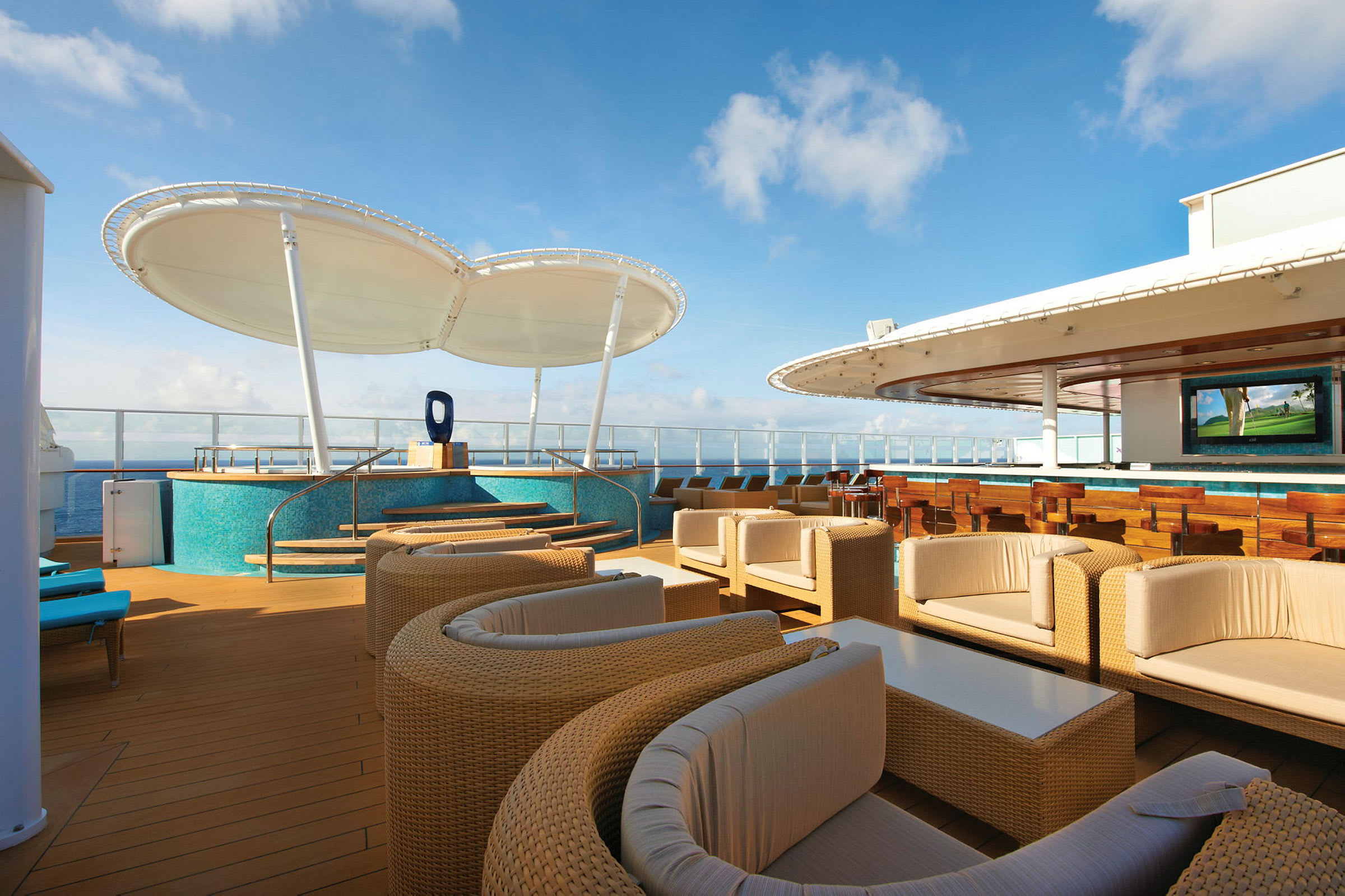 Terrasse med rottingmøbler, bar og TV-skjerm på et cruiseskip. (AI-generert tekst)