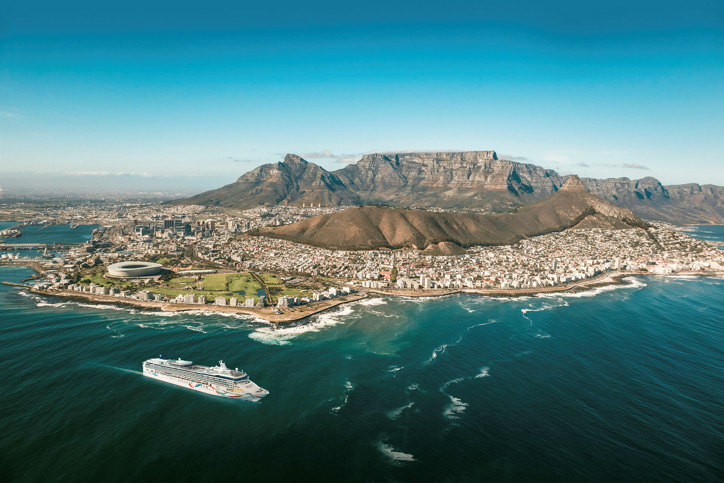 En utsikt over Cape Town, med Taffelberget i bakgrunnen og et cruiseskip på havet. (AI-generert tekst)