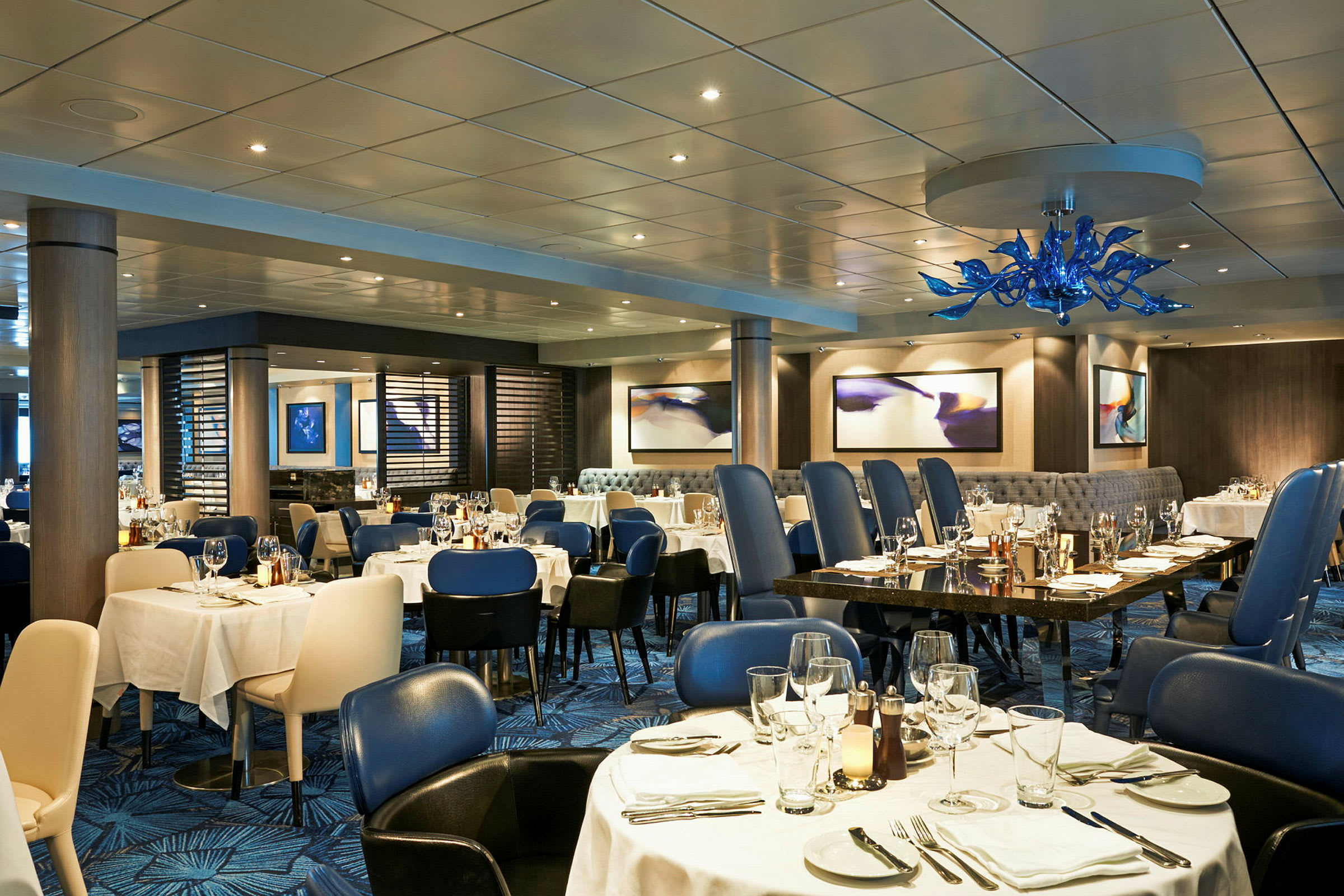 En elegant restaurant med dekkede bord og blå stoler. (AI-generert tekst)