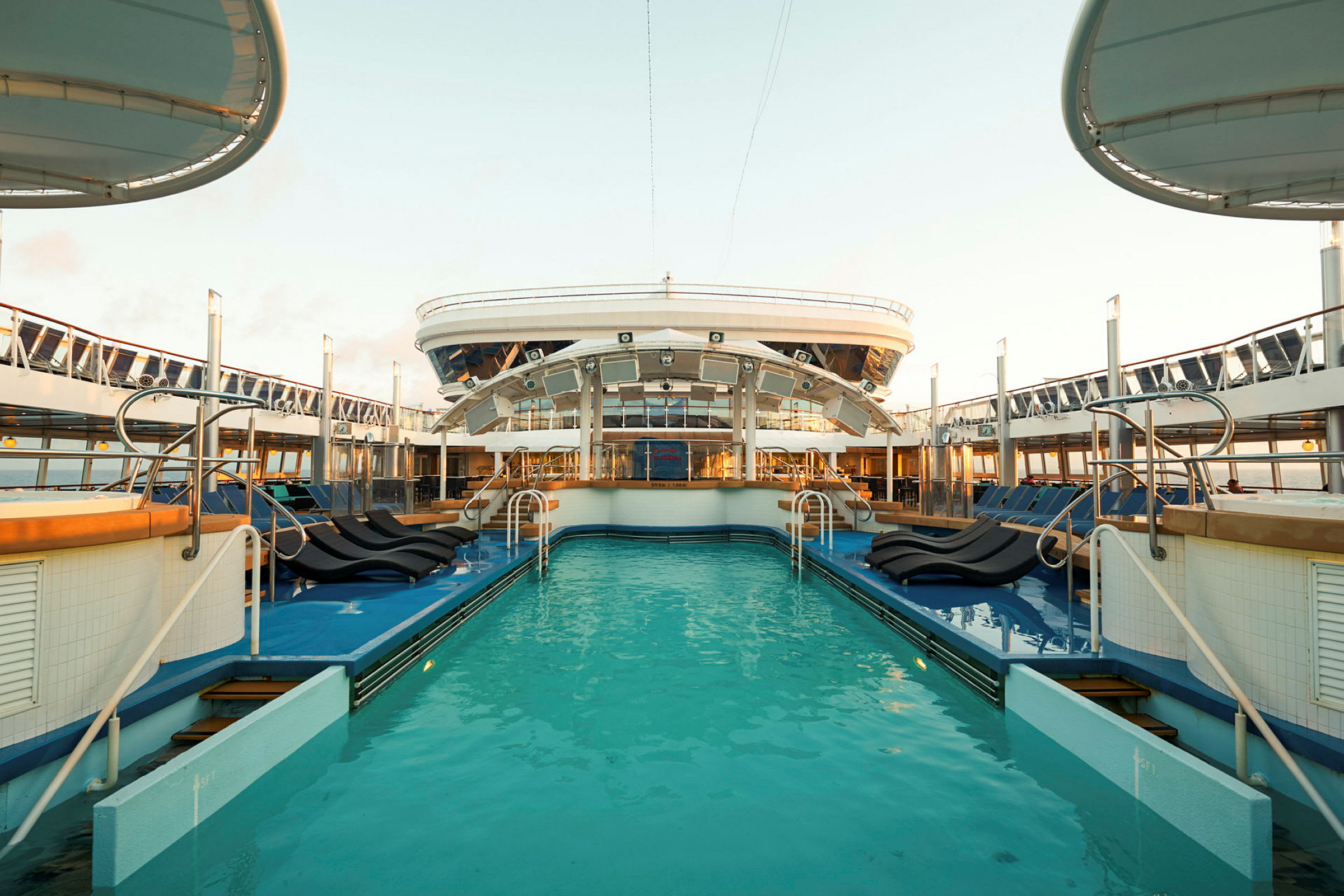 Et basseng med solsenger ombord på et cruiseskip. (AI-generert tekst)