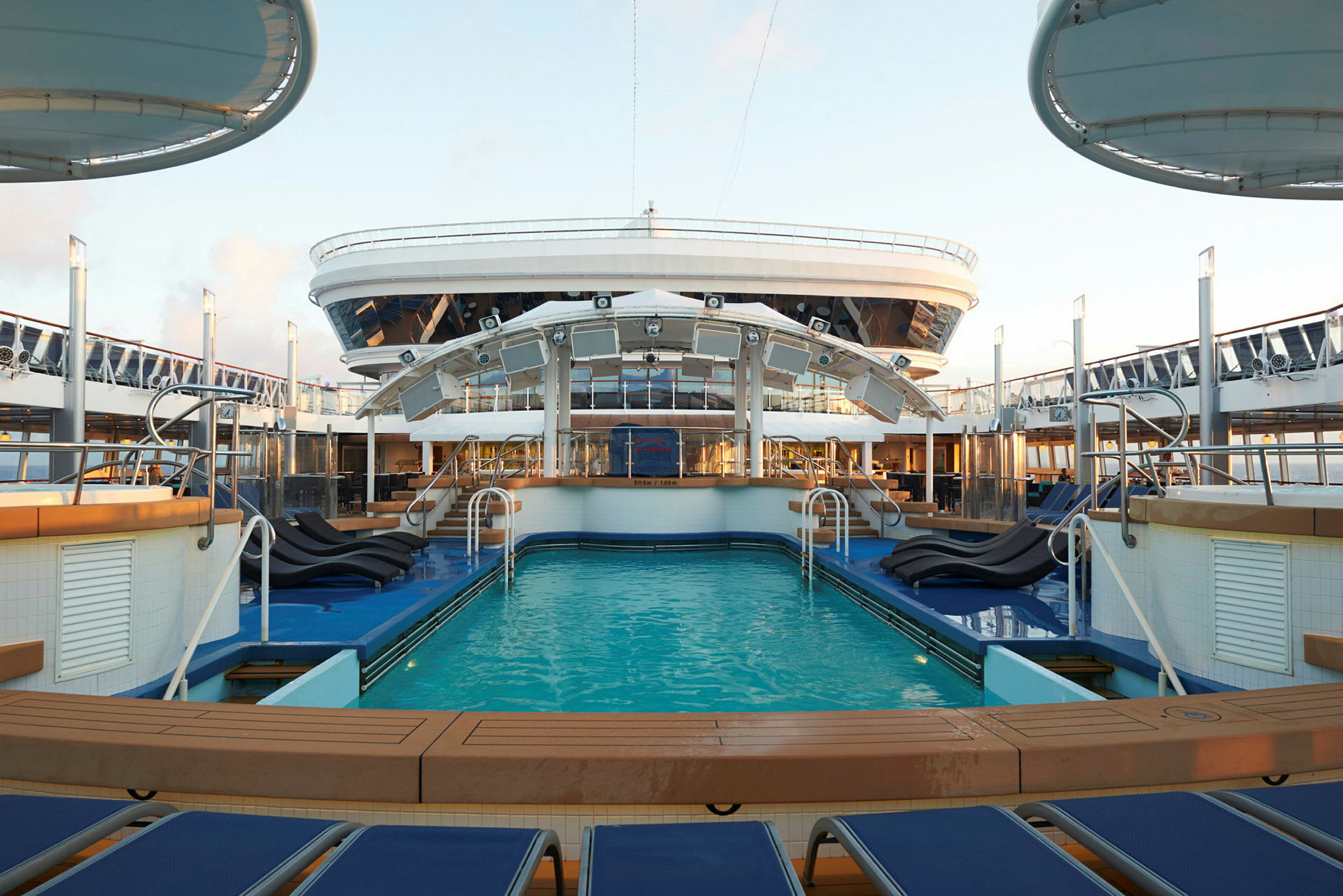 Et basseng på et cruiseskip med solsenger rundt. (AI-generert tekst)