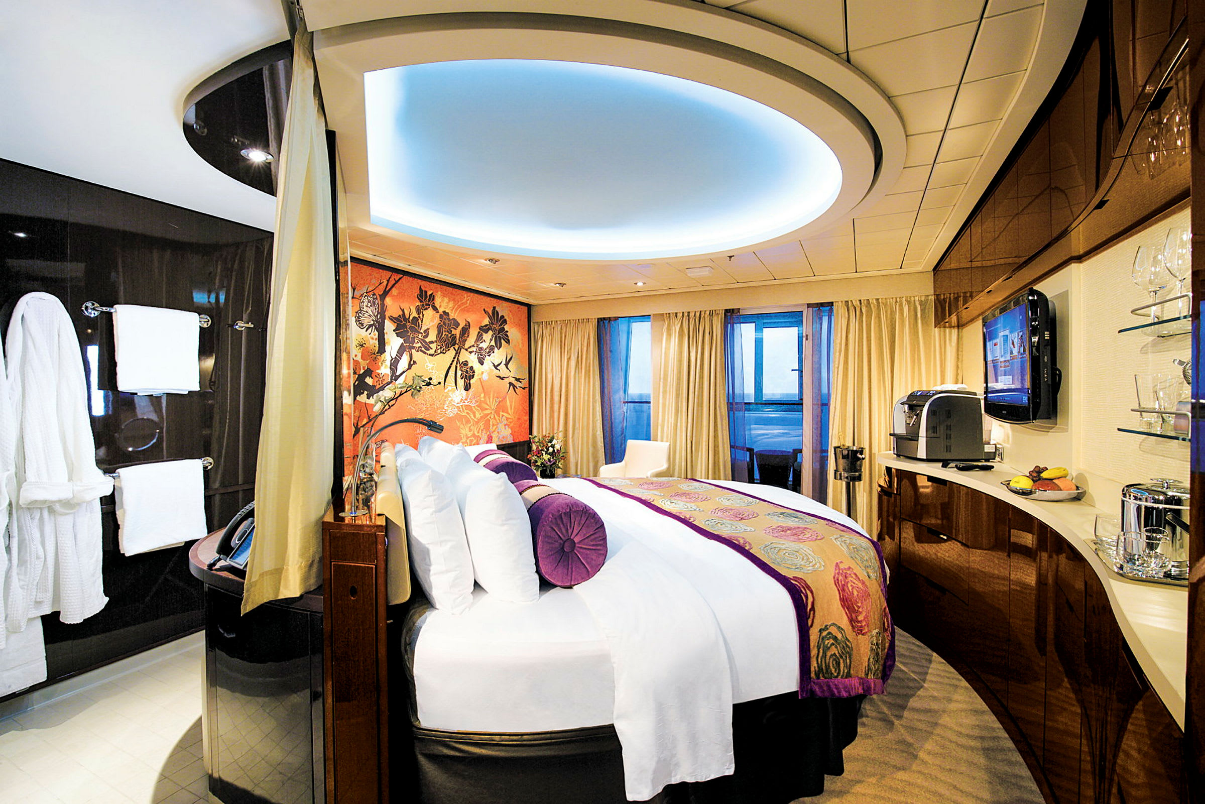 En moderne hotellsuite med en stor seng, fargerik tapet og fasiliteter som en kaffemaskin og en TV. (AI-generert tekst)