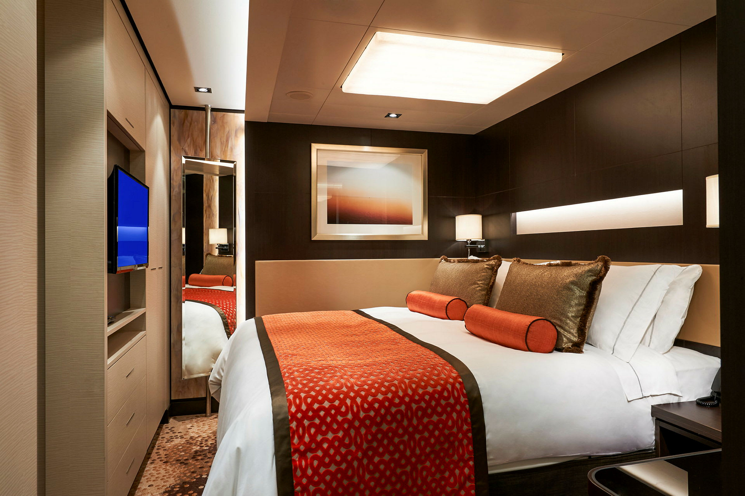 Et moderne innredet hotellrom med en dobbeltseng, fargede detaljer og en veggmontert TV. (AI-generert tekst)