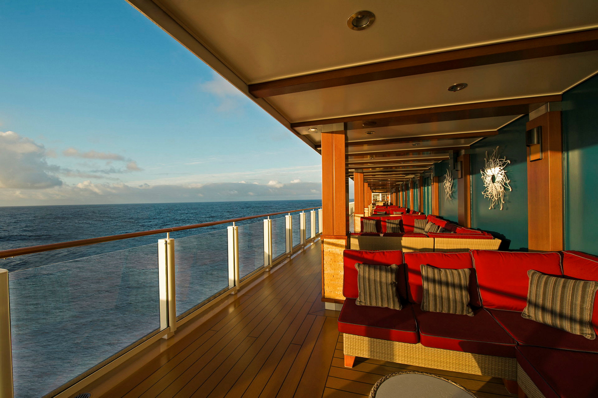 En overbygd terrasse med røde sittemøbler og utsikt over havet. (AI-generert tekst)