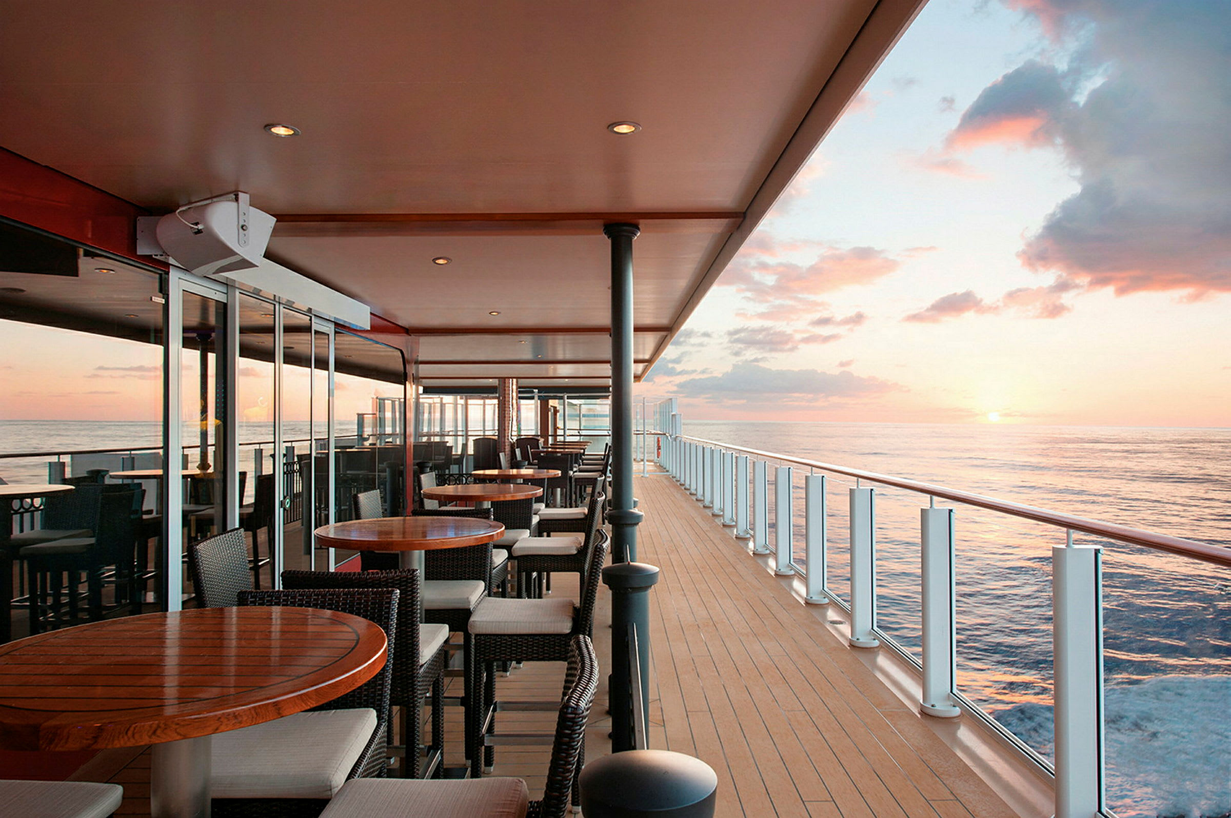 En utendørs kafé på et cruiseskip med havutsikt ved solnedgang. (AI-generert tekst)
