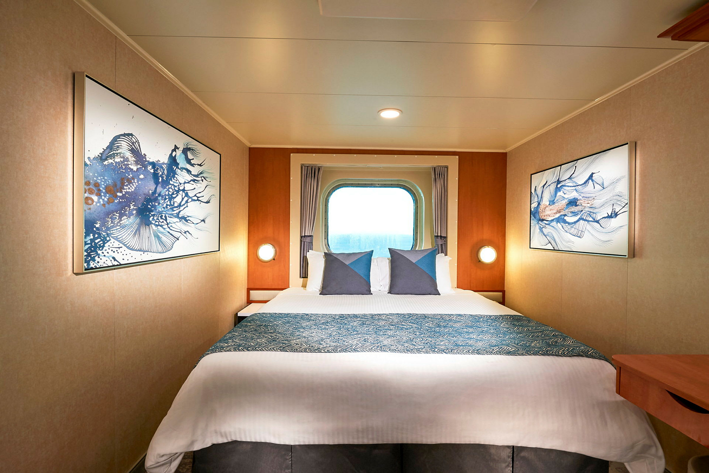 Moderne innredet cruisehytterom med en dobbeltseng. Et vindu gir utsikt mot havet, og vegger er dekorert med bilder av fiskemotiver. (AI-generert tekst)