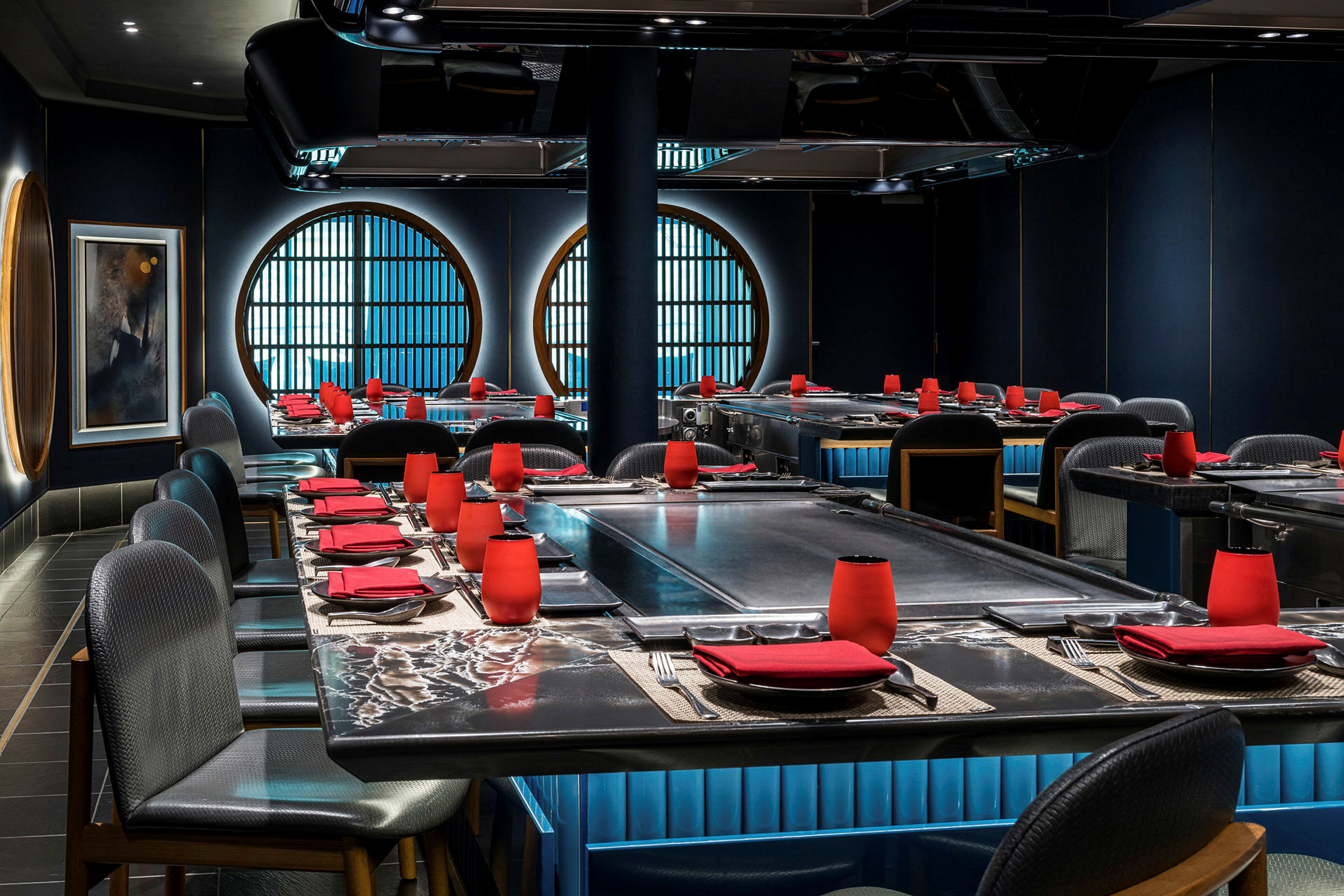 Bilde av en elegant restaurant med mørk innredning, røde detaljer og store sirkulære vinduer. (AI-generert tekst)